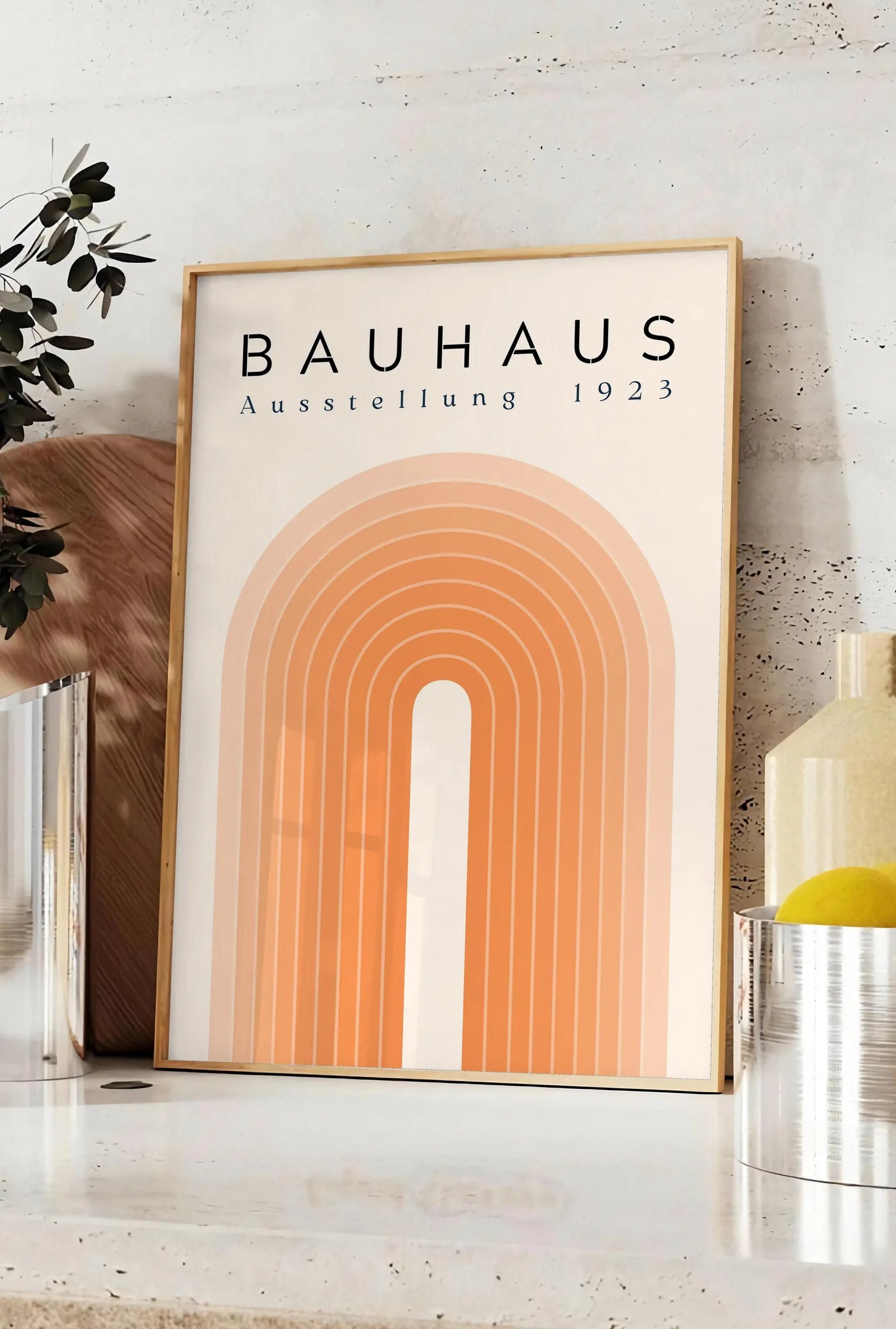 Affiche sabliers Noirs, posee sur un plan de travail de cuisine en pierre claire, entre une branche d'eucalyptus en vase et un bocal de citrons