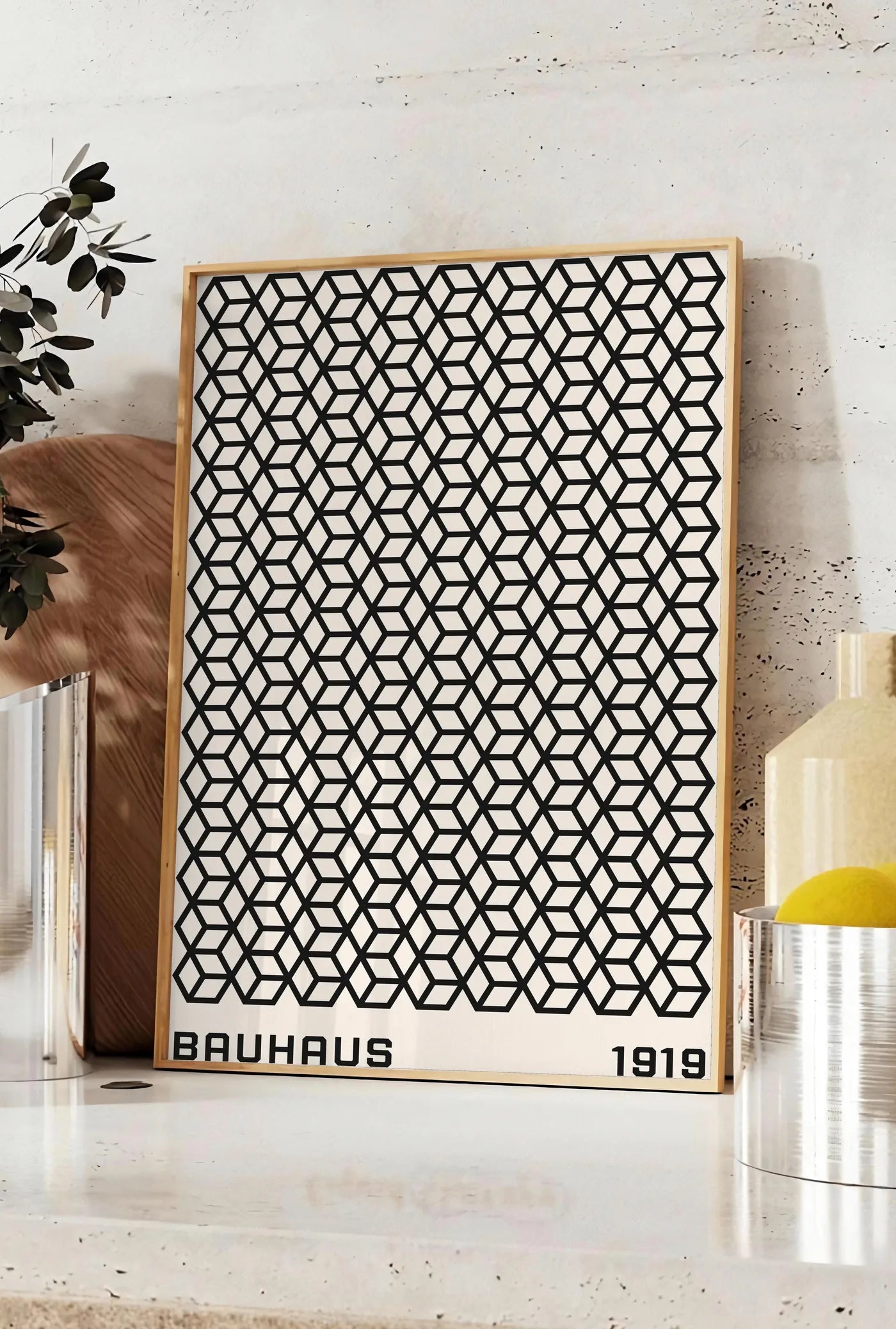 Affiche treillis de Cubes, posee sur un plan de travail de cuisine en pierre claire, entre une branche d'eucalyptus en vase et un bocal de citrons