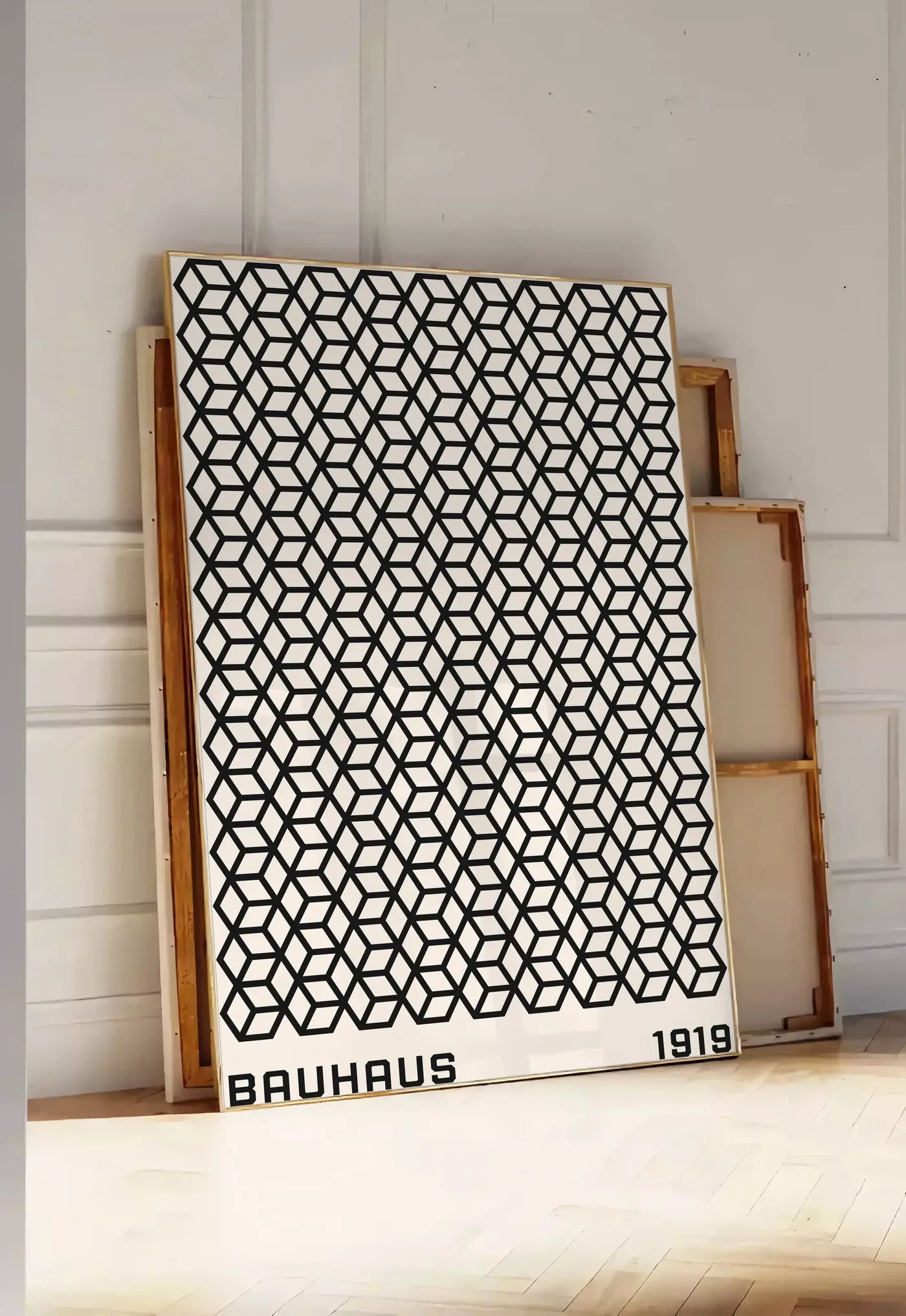 Tirage encadrable treillis de Cubes, posee au sol dans une entree lumineuse, contre un mur a panneaux blancs, a cote de chassis en bois empiles
