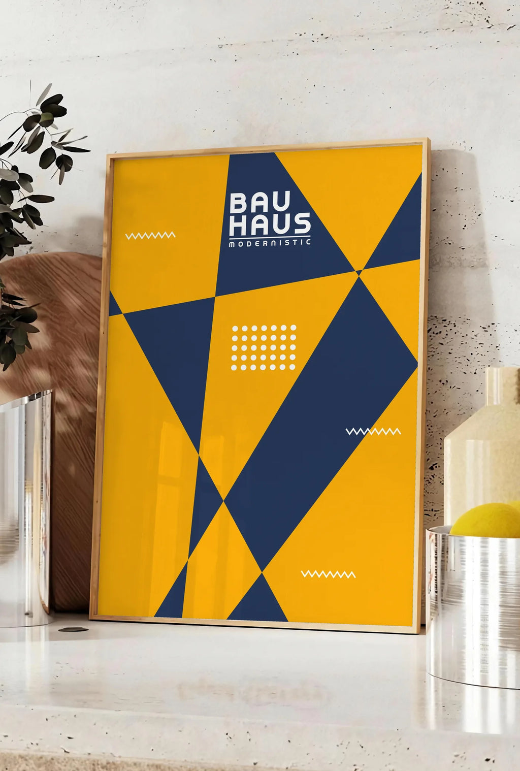 Affiche triangles Modernistic, posee sur un plan de travail de cuisine en pierre claire, entre une branche d'eucalyptus en vase et un bocal de citrons