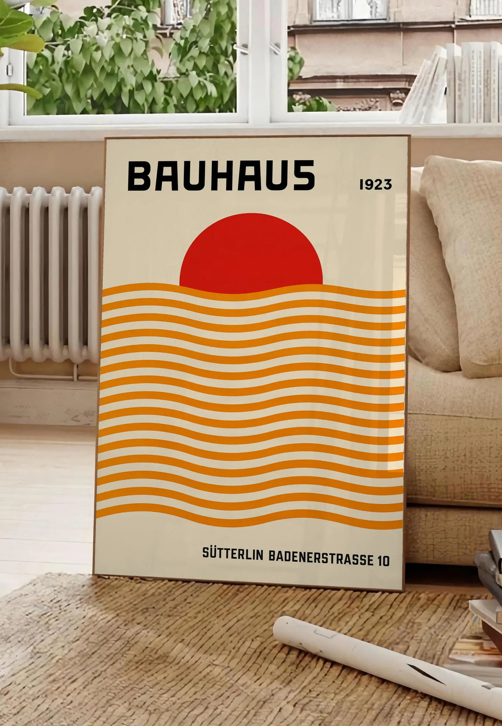 Poster vagues Orange et Soleil, posee au sol dans un salon parisien, devant une grande fenetre donnant sur un immeuble haussmannien, entre un ficus et un canape creme