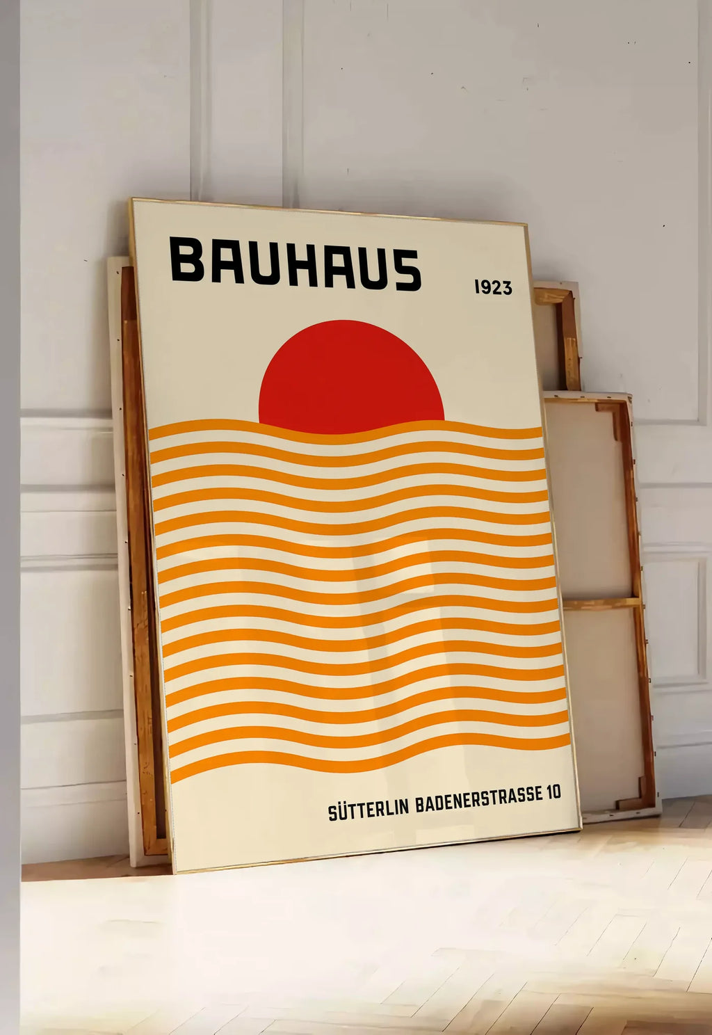 Tirage encadrable vagues Orange et Soleil, posee au sol dans une entree lumineuse, contre un mur a panneaux blancs, a cote de chassis en bois empiles