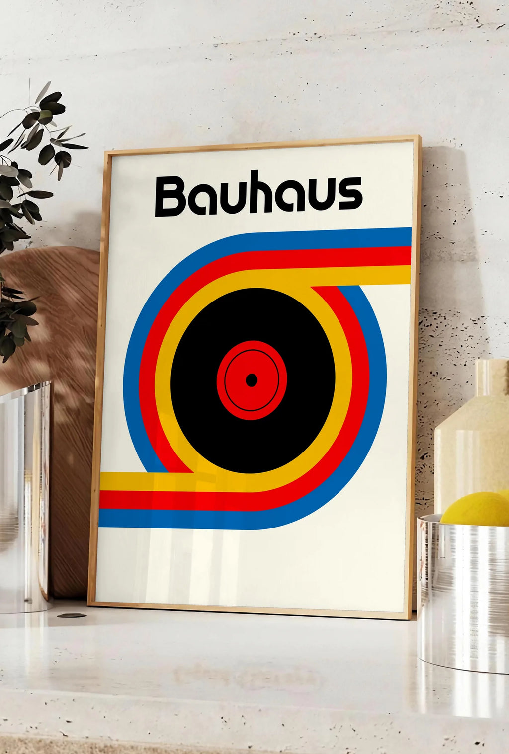 Affiche vinyle et Ruban, posee sur un plan de travail de cuisine en pierre claire, entre une branche d'eucalyptus en vase et un bocal de citrons