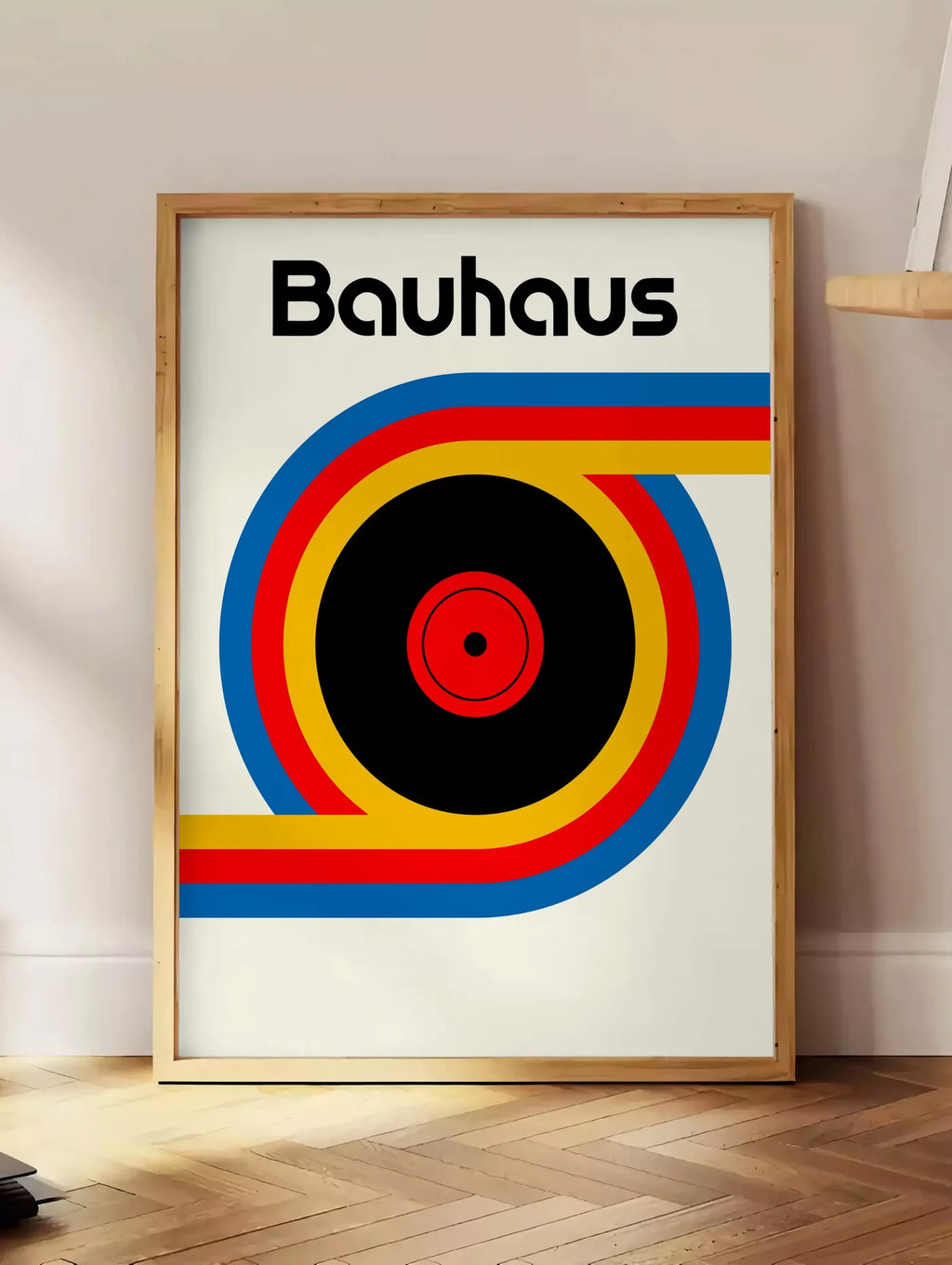 Estampe vinyle et Ruban, posee au sol dans un coin salon, sur un parquet a chevrons, pres d'une table d'appoint en chene chargee de livres