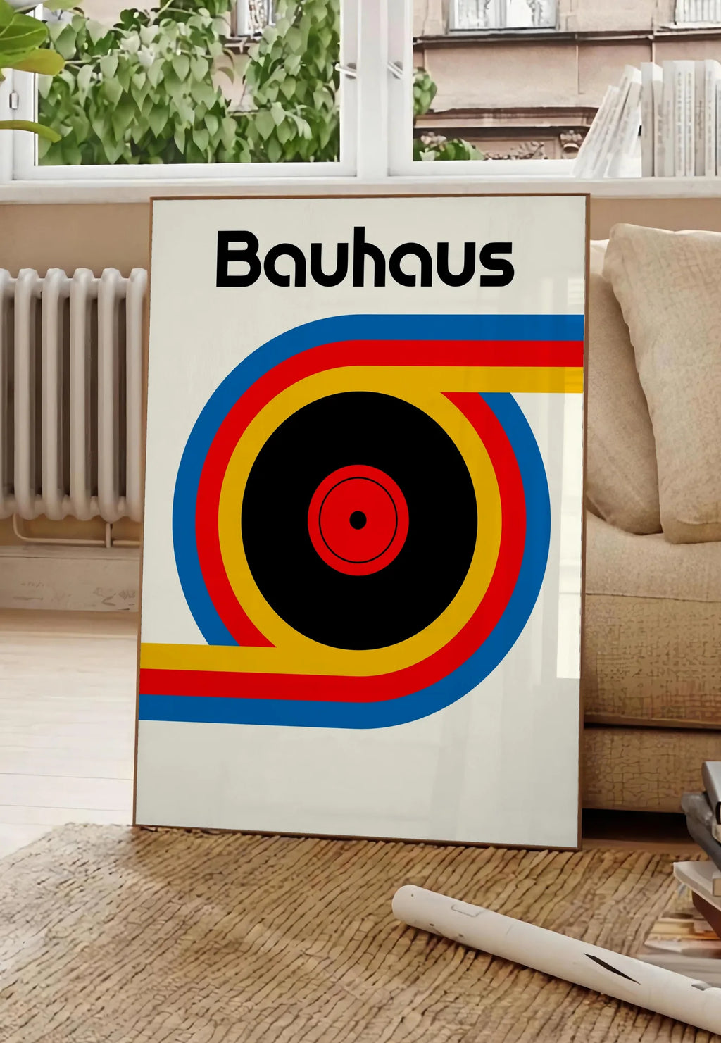 Poster vinyle et Ruban, posee au sol dans un salon parisien, devant une grande fenetre donnant sur un immeuble haussmannien, entre un ficus et un canape creme