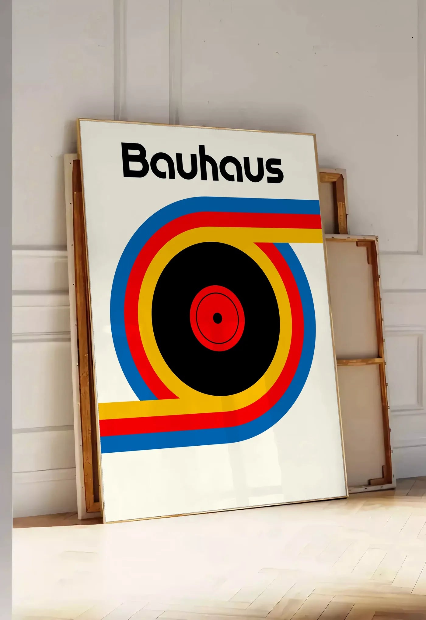 Tirage encadrable vinyle et Ruban, posee au sol dans une entree lumineuse, contre un mur a panneaux blancs, a cote de chassis en bois empiles