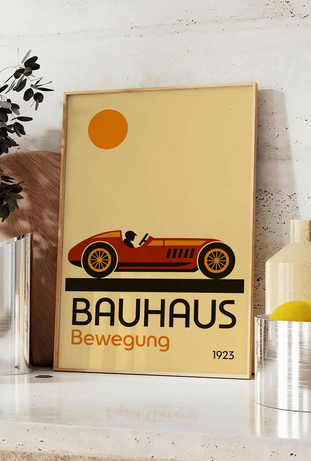 Affiche voiture de Course, posee sur un plan de travail de cuisine en pierre claire, entre une branche d'eucalyptus en vase et un bocal de citrons