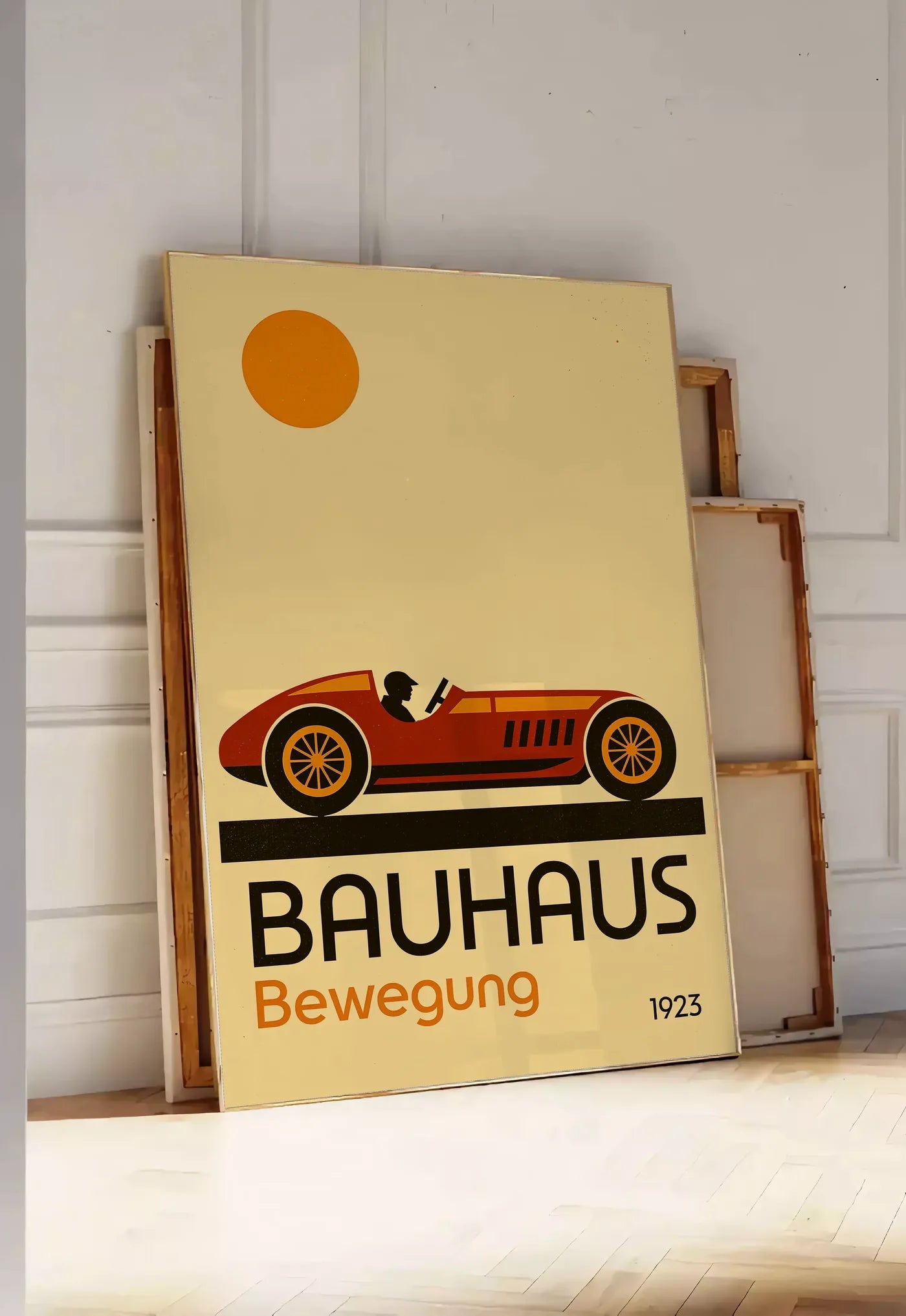 Tirage encadrable voiture de Course, posee au sol dans une entree lumineuse, contre un mur a panneaux blancs, a cote de chassis en bois empiles
