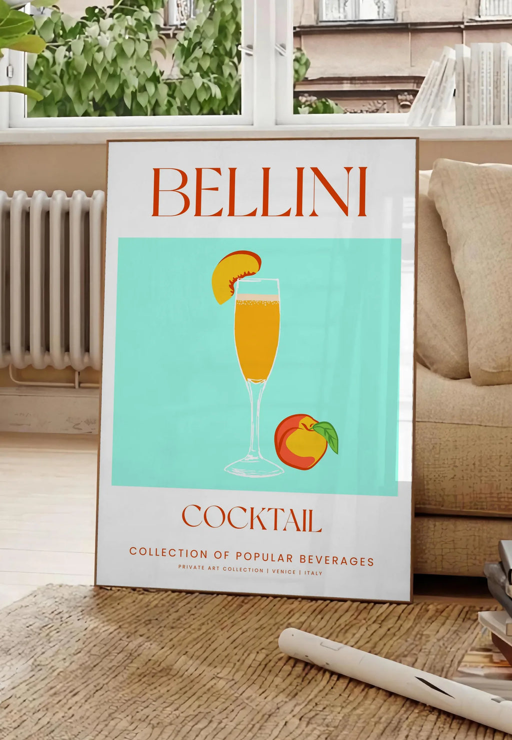 Poster affiche cocktail Bellini, posee au sol dans un salon parisien, devant une grande fenetre donnant sur un immeuble haussmannien, entre un ficus et un canape creme