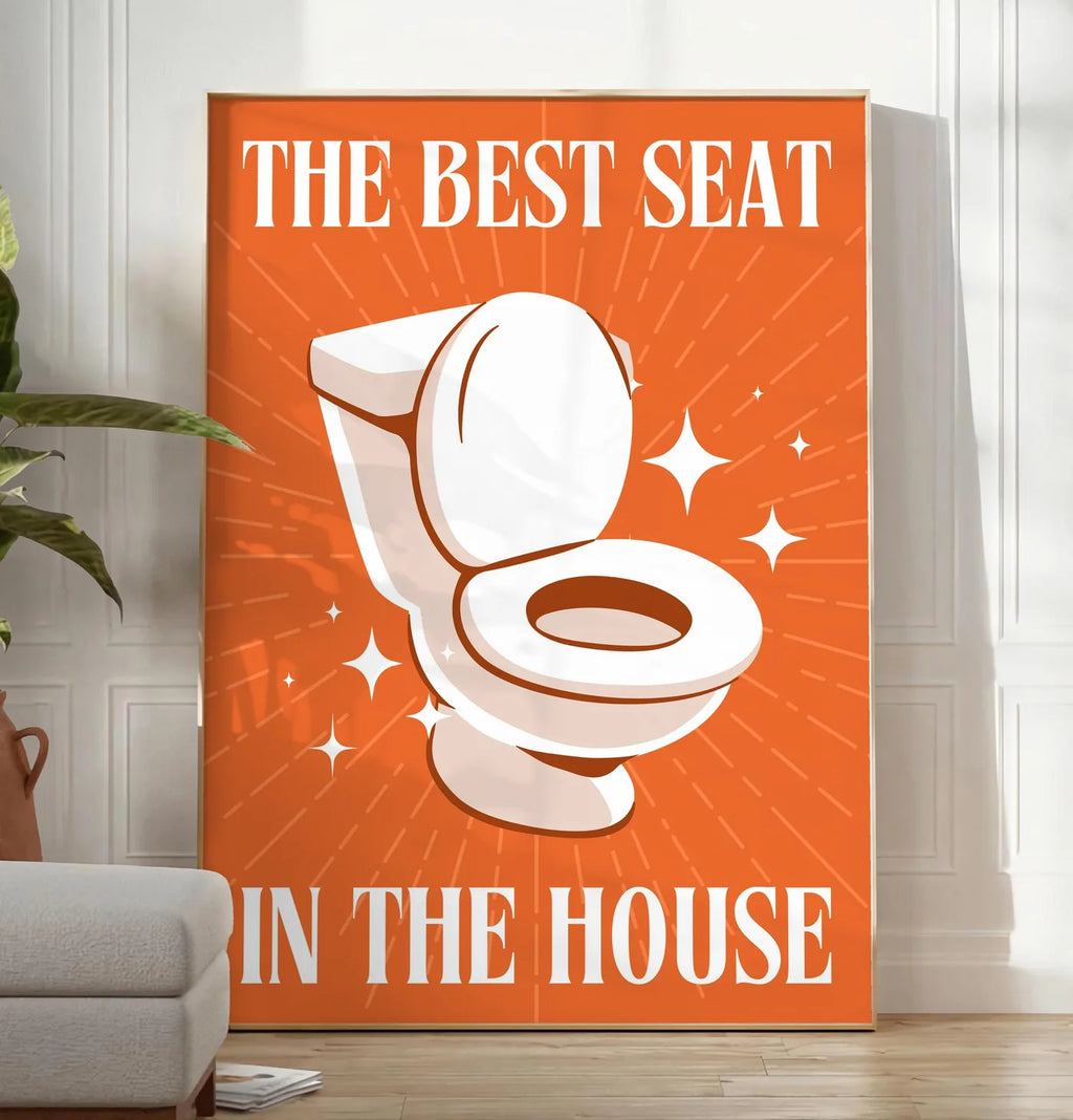 Reproduction affiche toilettes humour, posee au sol dans un salon minimaliste clair, a cote d'un canape beige et d'une plante verte, sur un parquet clair