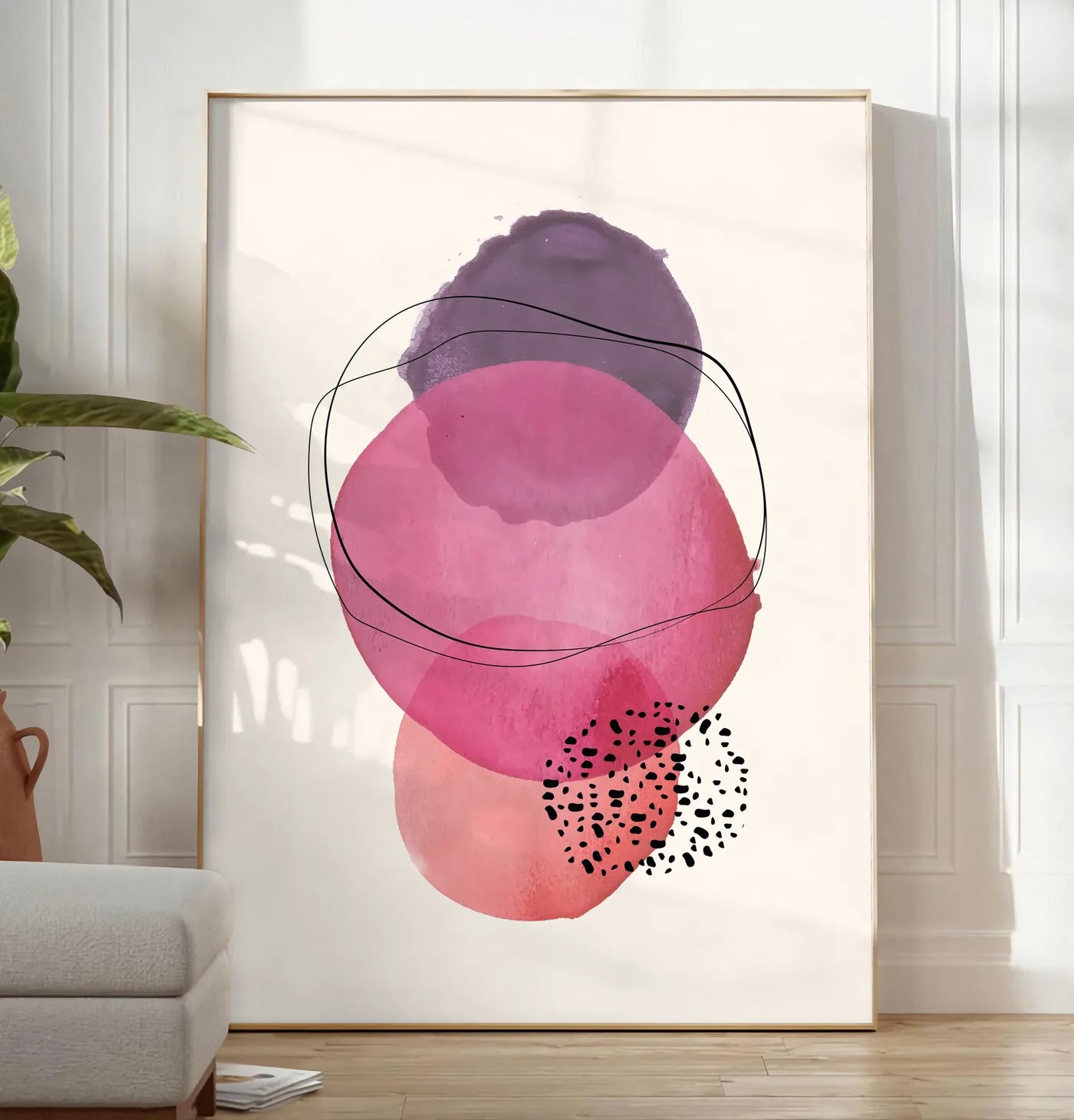 Reproduction cercles aquarelle roses magenta et violets superposes sur creme, posee au sol dans un salon minimaliste clair, a cote d'un canape beige et d'une plante verte, sur un parquet clair