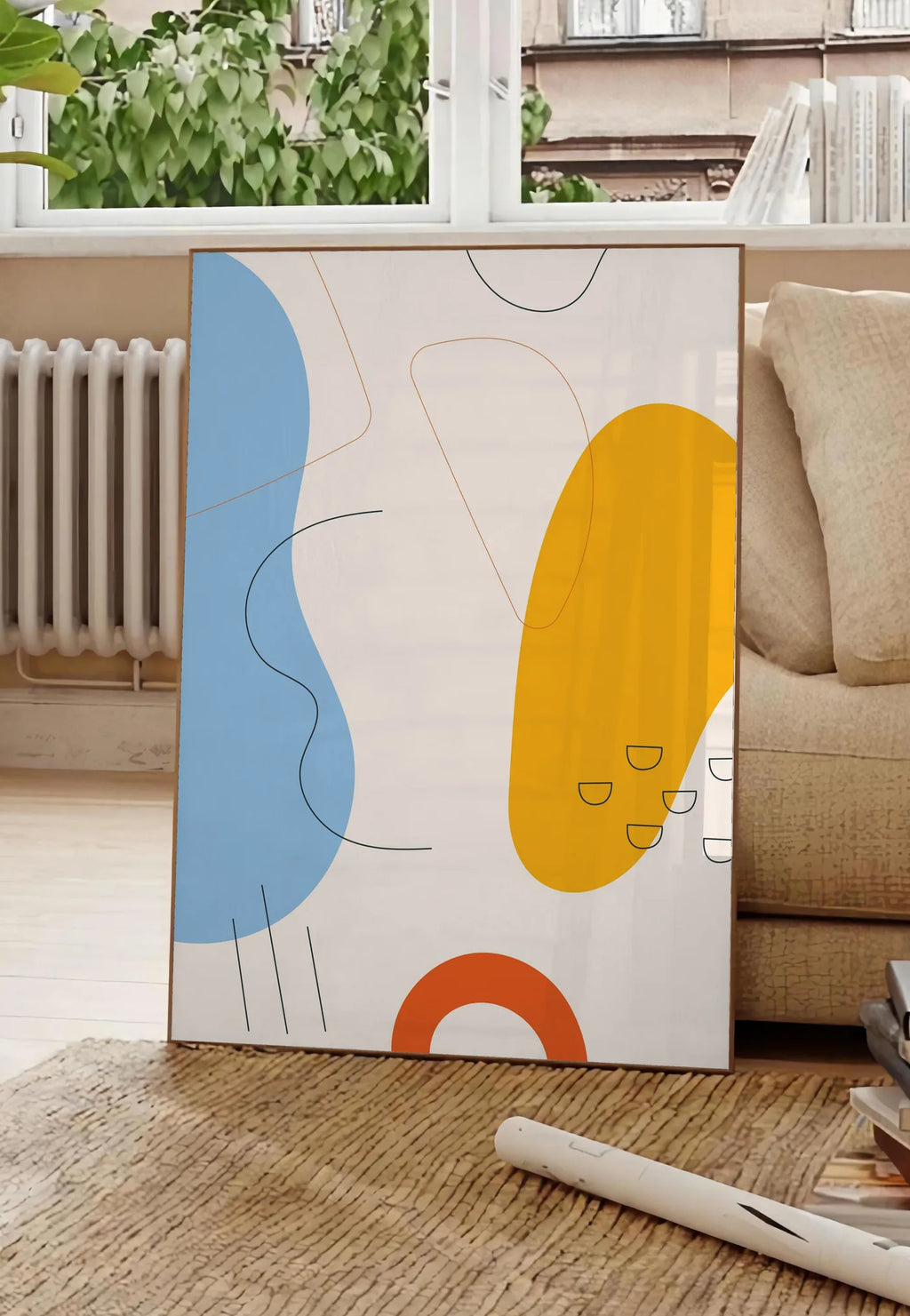 Poster formes organiques bleu et jaune avec traits fins sur fond creme, posee au sol dans un salon parisien, devant une grande fenetre donnant sur un immeuble haussmannien, entre un ficus et un canape creme
