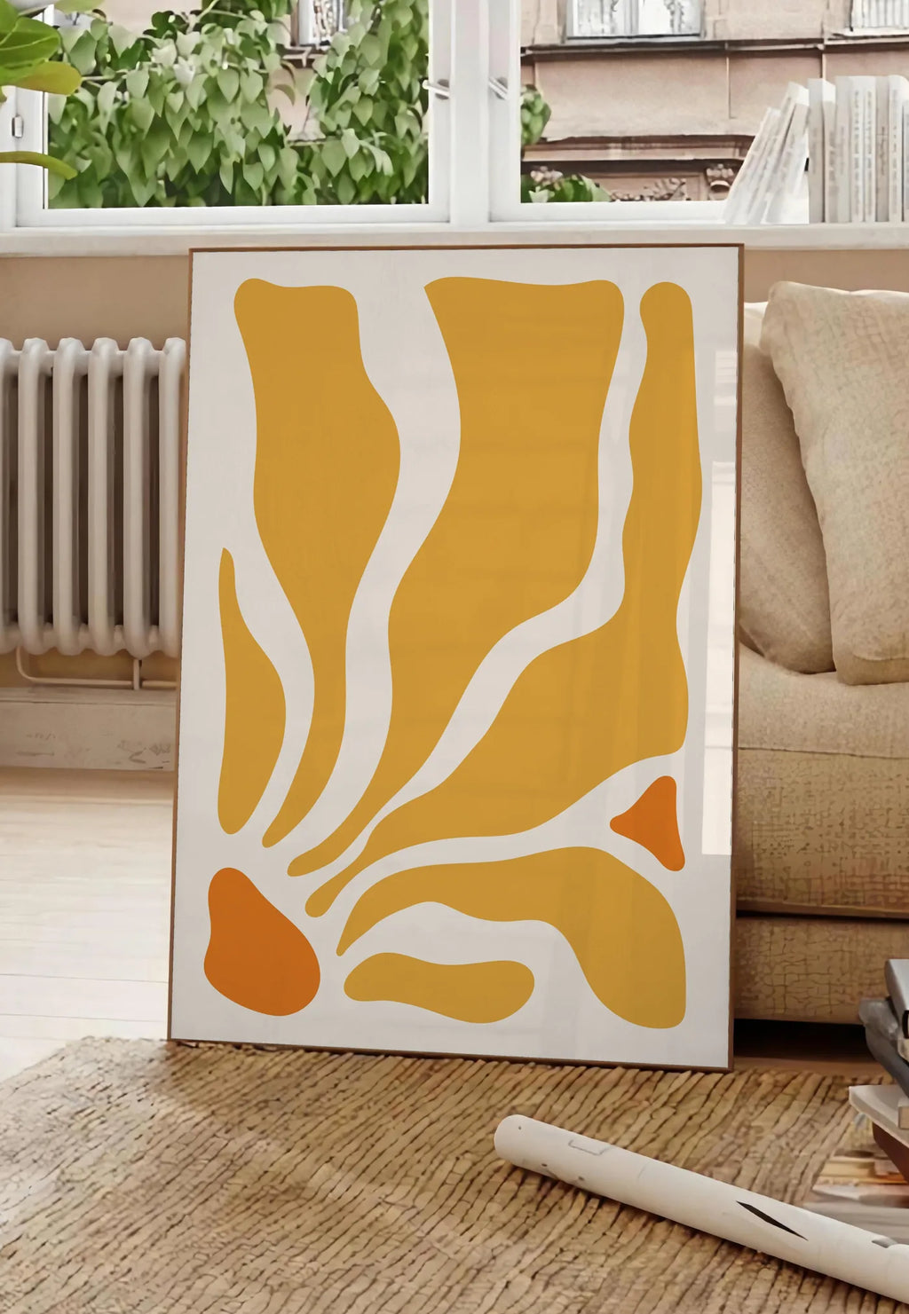 Poster formes organiques jaunes et orange ondulees sur fond creme, posee au sol dans un salon parisien, devant une grande fenetre donnant sur un immeuble haussmannien, entre un ficus et un canape creme