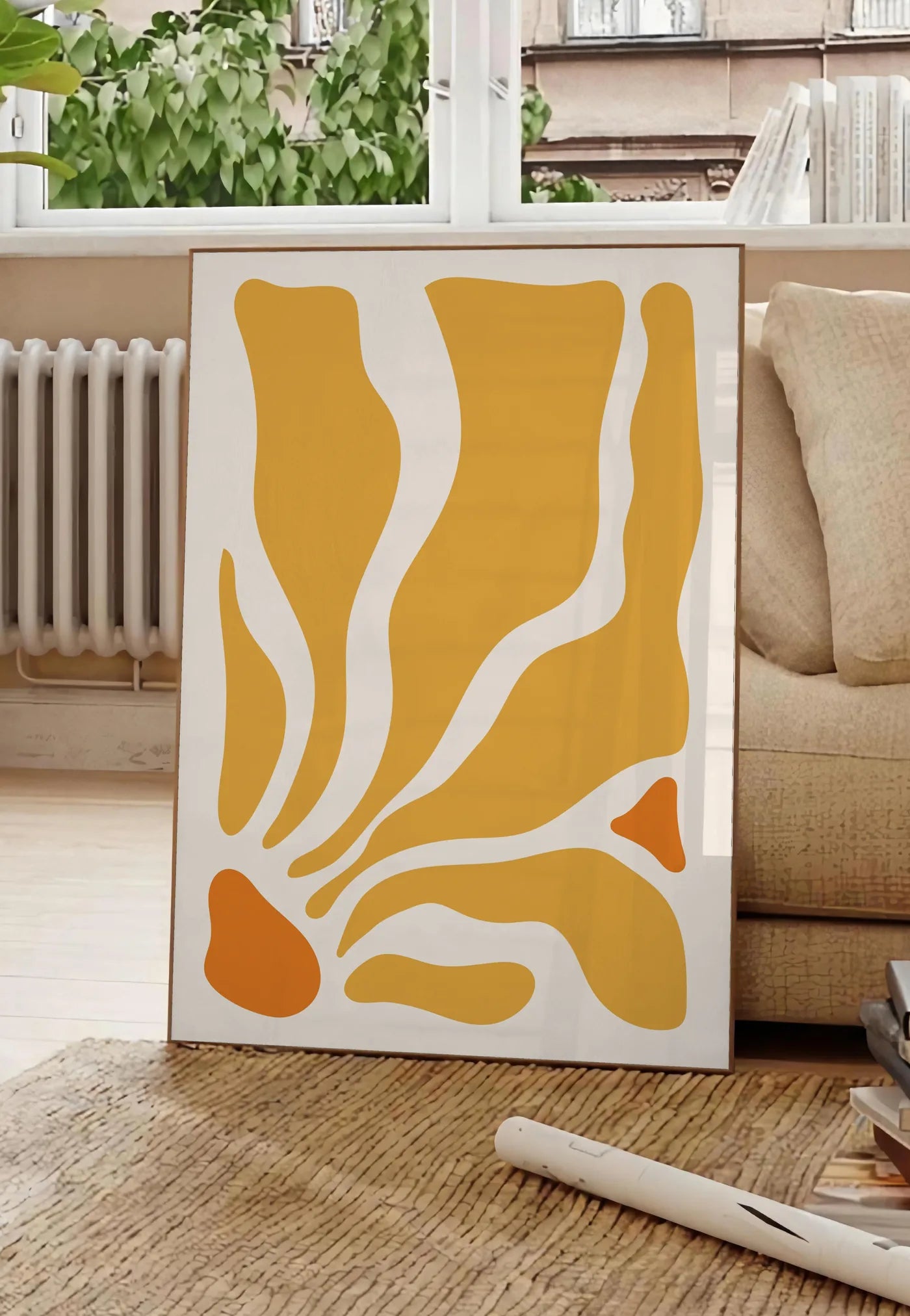 Poster formes organiques jaunes et orange ondulees sur fond creme, posee au sol dans un salon parisien, devant une grande fenetre donnant sur un immeuble haussmannien, entre un ficus et un canape creme