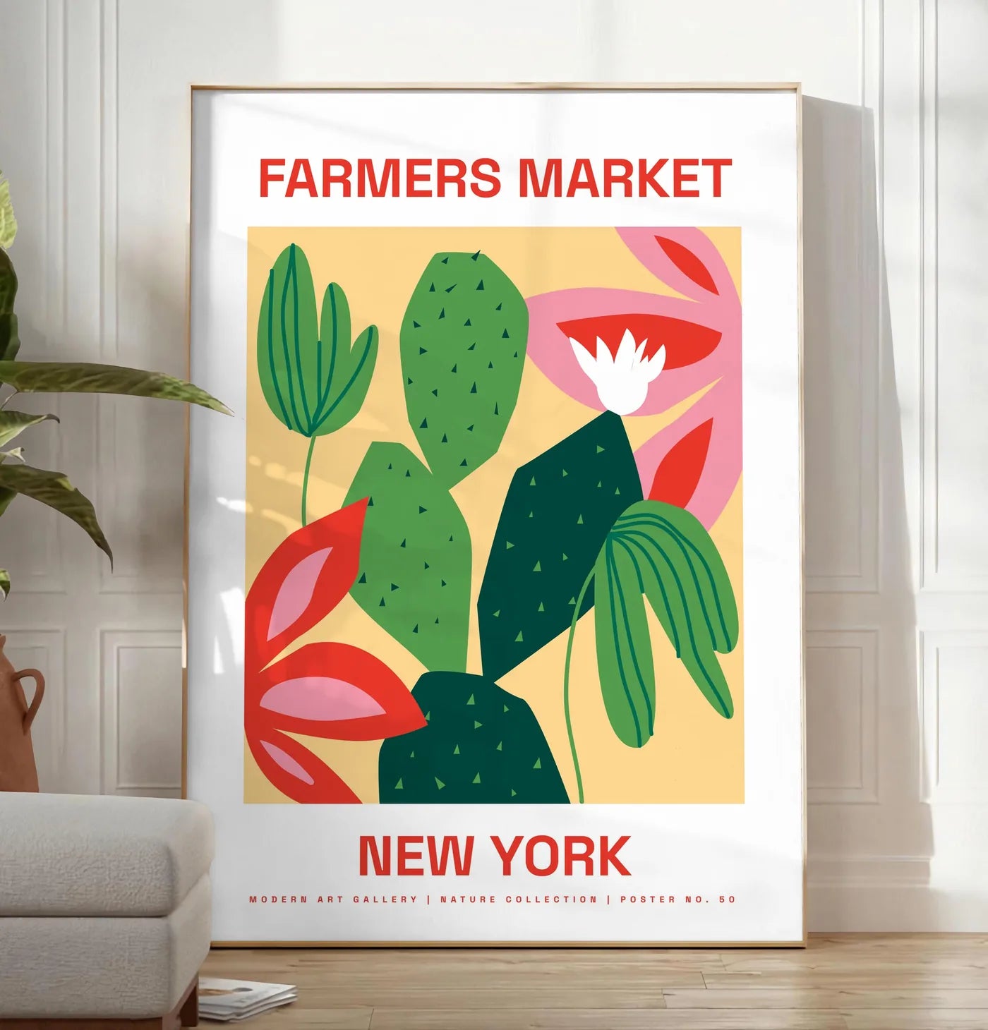 Reproduction affiche botanique cactus et feuilles rayees, posee au sol dans un salon minimaliste clair, a cote d'un canape beige et d'une plante verte, sur un parquet clair