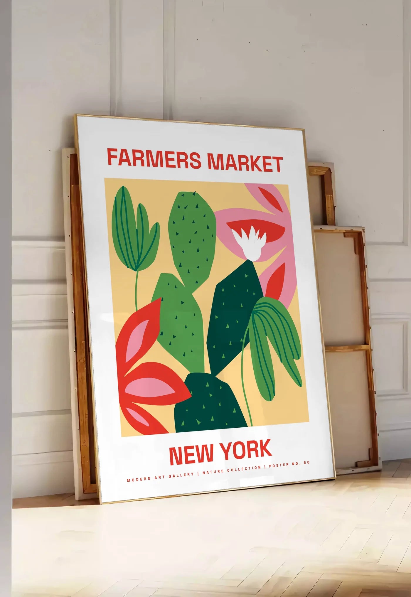 Tirage encadrable affiche botanique cactus et feuilles rayees, posee au sol dans une entree lumineuse, contre un mur a panneaux blancs, a cote de chassis en bois empiles