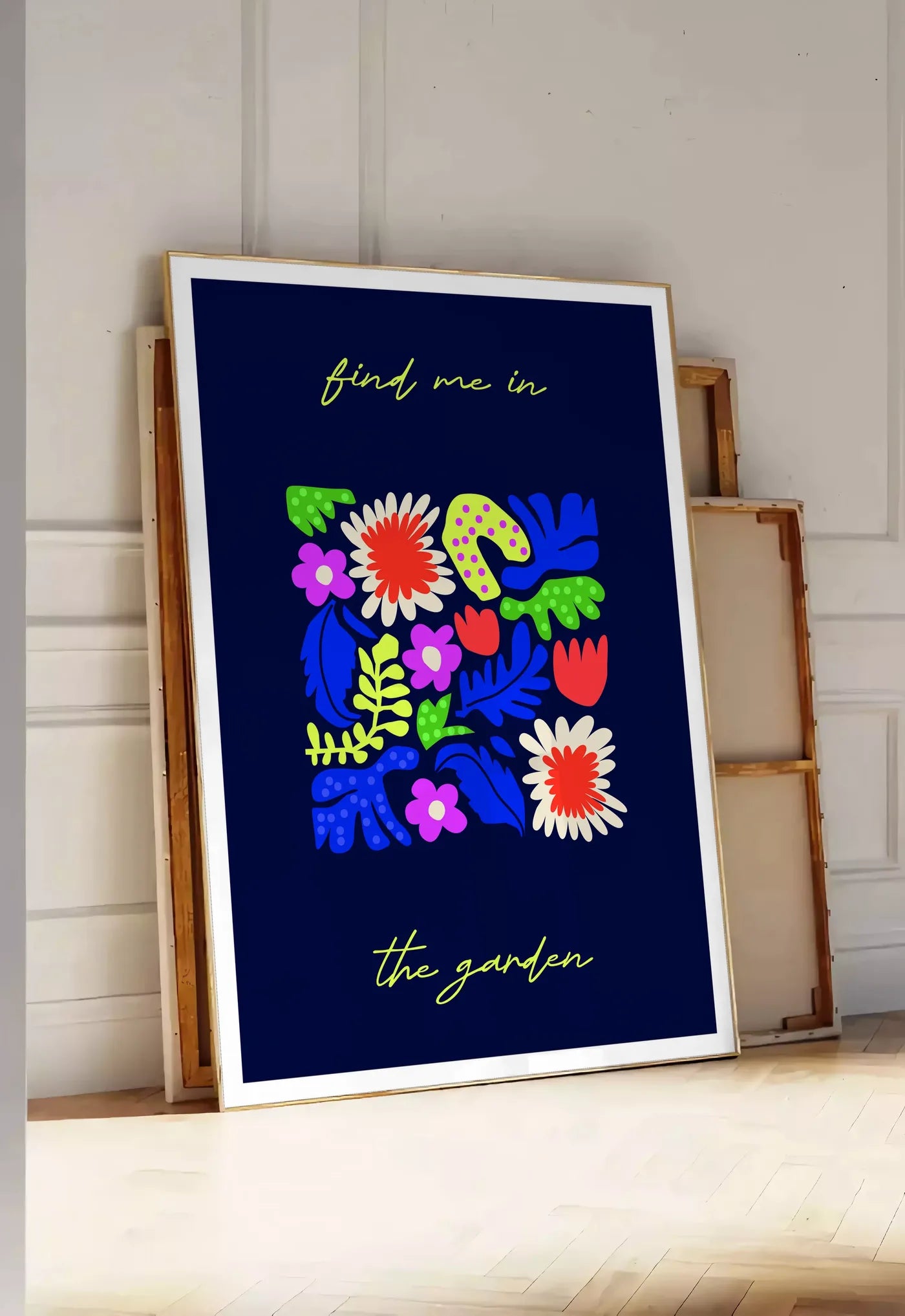 Tirage encadrable affiche botanique fleurs folk, posee au sol dans une entree lumineuse, contre un mur a panneaux blancs, a cote de chassis en bois empiles