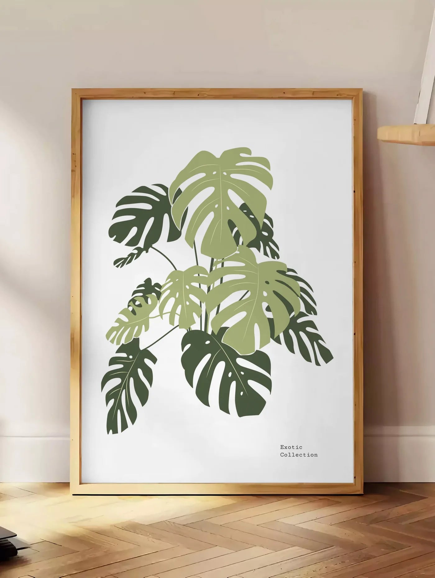 Estampe affiche monstera botanique, posee au sol dans un coin salon, sur un parquet a chevrons, pres d'une table d'appoint en chene chargee de livres