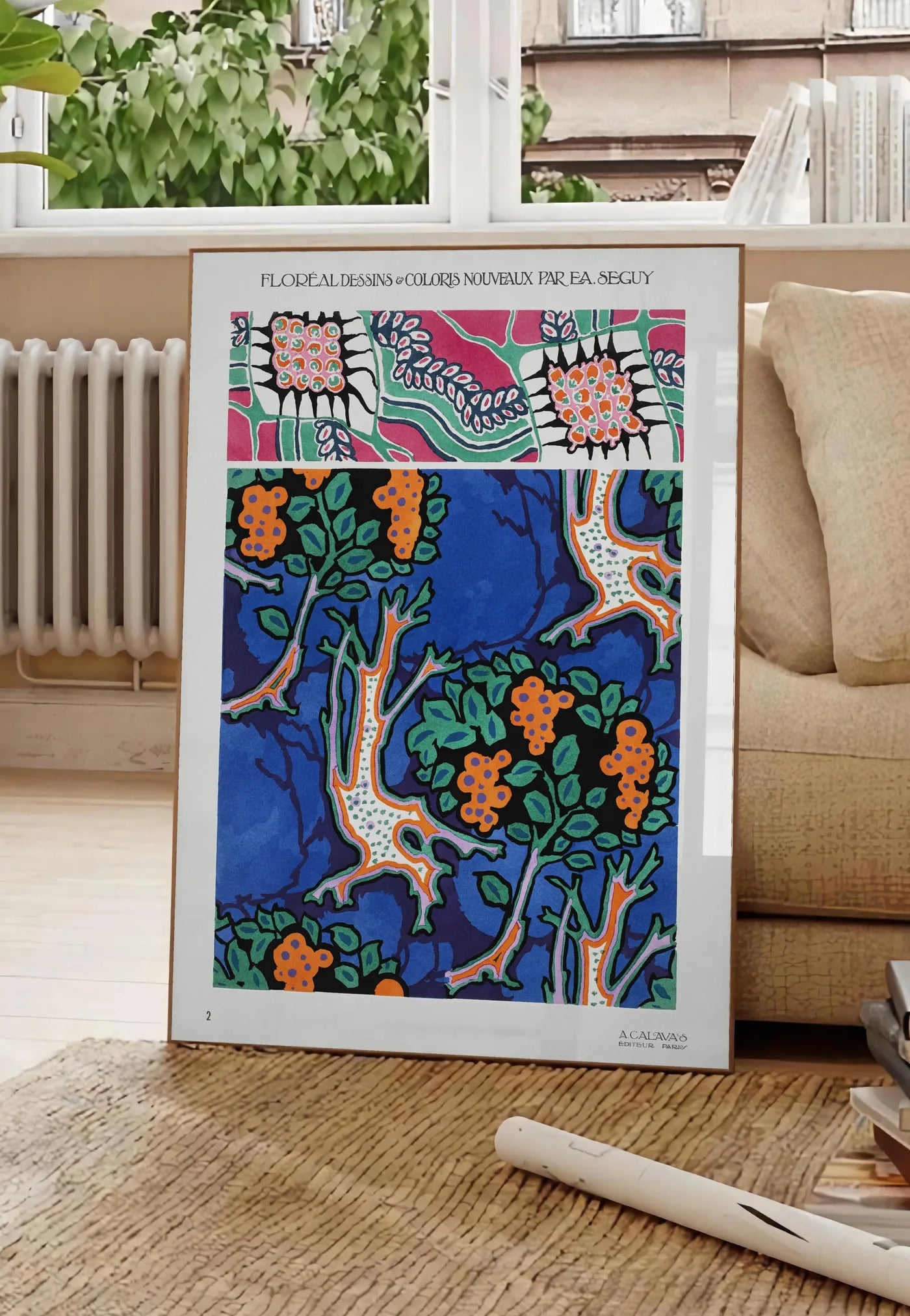 Poster planches botaniques montrent des grappes de fruits stylisées sur fond bleu de cobalt, posee au sol dans un salon parisien, devant une grande fenetre donnant sur un immeuble haussmannien, entre un ficus et un canape creme