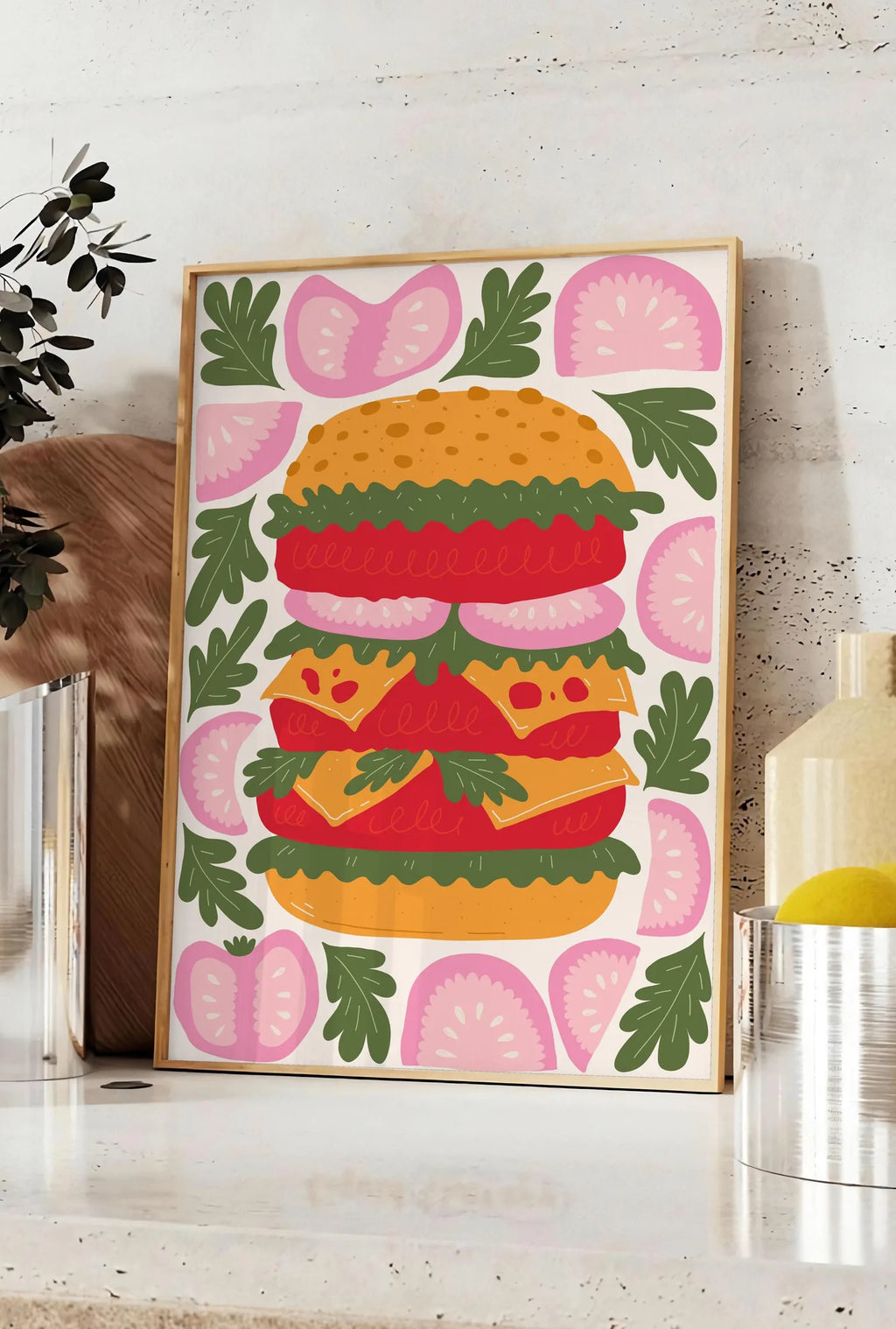 Affiche affiche cuisine burger, posee sur un plan de travail de cuisine en pierre claire, entre une branche d'eucalyptus en vase et un bocal de citrons