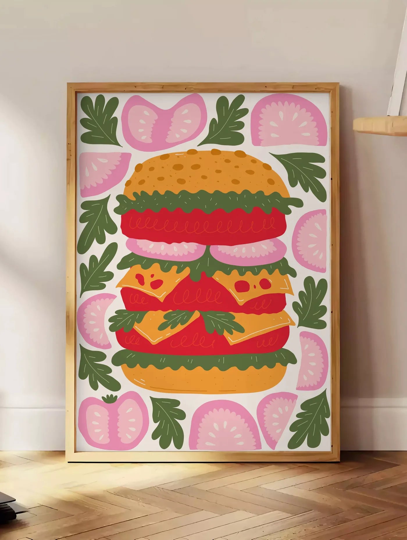 Estampe affiche cuisine burger, posee au sol dans un coin salon, sur un parquet a chevrons, pres d'une table d'appoint en chene chargee de livres