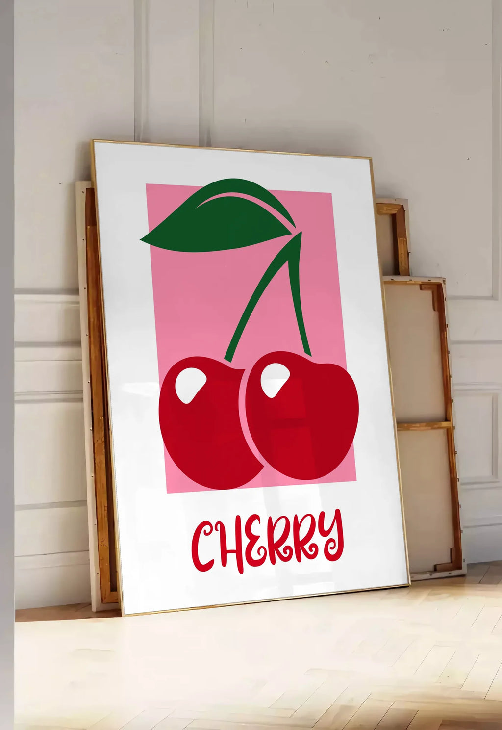 Tirage encadrable affiche cuisine cerises cherry fruit rouges et feuille verte sur panneau rose, posee au sol dans une entree lumineuse, contre un mur a panneaux blancs, a cote de chassis en bois empiles