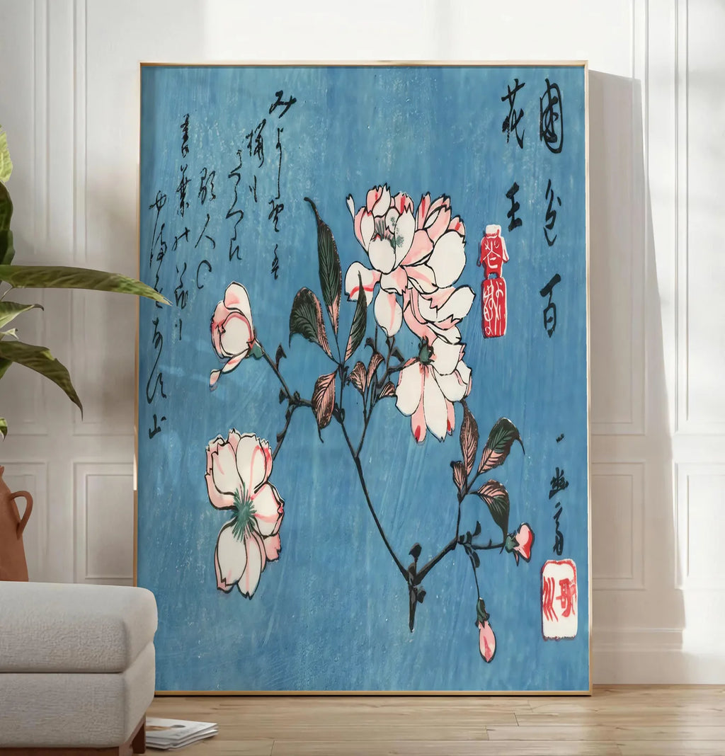 Reproduction affiche cerisier en fleurs sur fond bleu art japonais, posee au sol dans un salon minimaliste clair, a cote d'un canape beige et d'une plante verte, sur un parquet clair