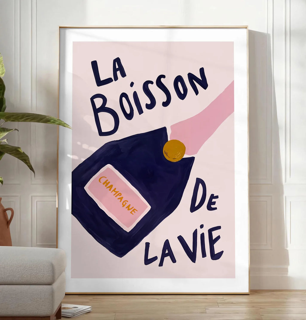 Reproduction affiche champagne La Boisson de la Vie, posee au sol dans un salon minimaliste clair, a cote d'un canape beige et d'une plante verte, sur un parquet clair