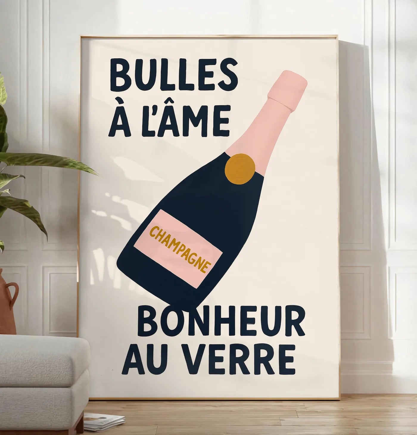 Reproduction affiche champagne Bulles a l'ame, posee au sol dans un salon minimaliste clair, a cote d'un canape beige et d'une plante verte, sur un parquet clair