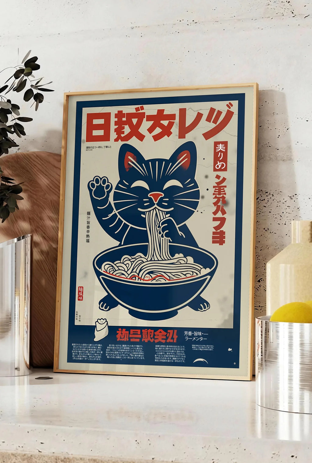 Affiche affiche chat ramen retro, posee sur un plan de travail de cuisine en pierre claire, entre une branche d'eucalyptus en vase et un bocal de citrons