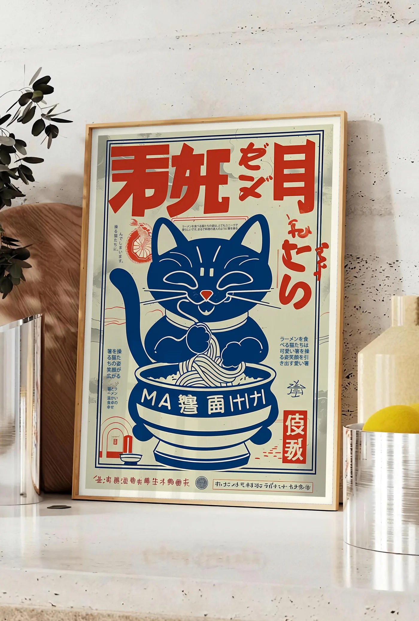 Affiche affiche chat ramen vintage, posee sur un plan de travail de cuisine en pierre claire, entre une branche d'eucalyptus en vase et un bocal de citrons
