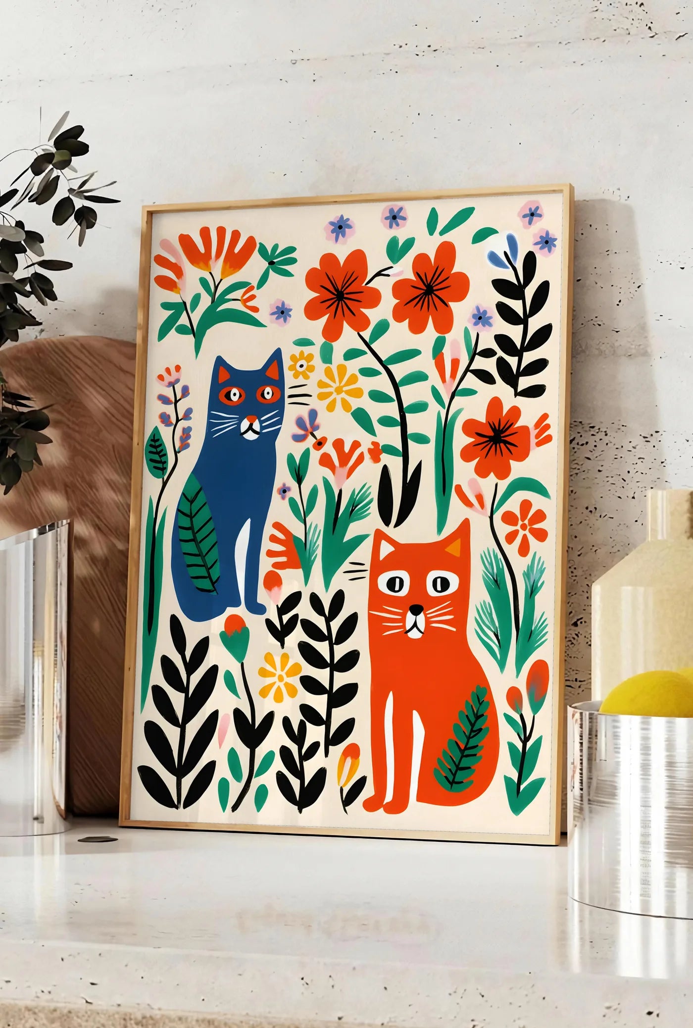 Affiche affiche chats art naif, posee sur un plan de travail de cuisine en pierre claire, entre une branche d'eucalyptus en vase et un bocal de citrons
