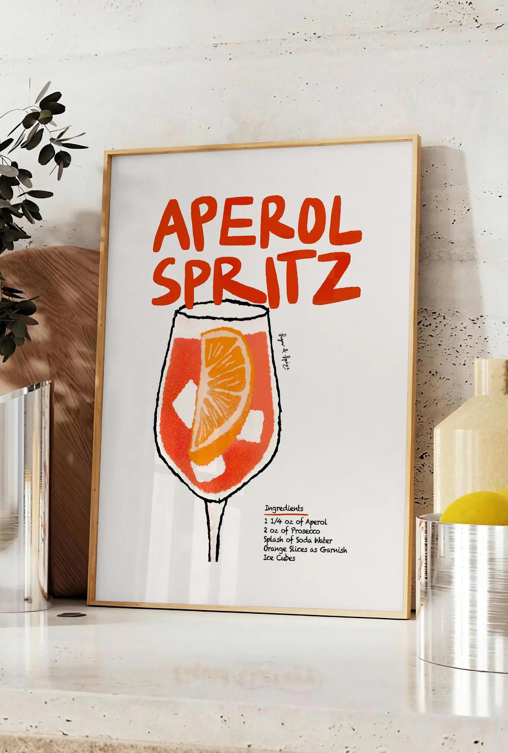 Affiche verre d'Aperol Spritz, posee sur un plan de travail de cuisine en pierre claire, entre une branche d'eucalyptus en vase et un bocal de citrons