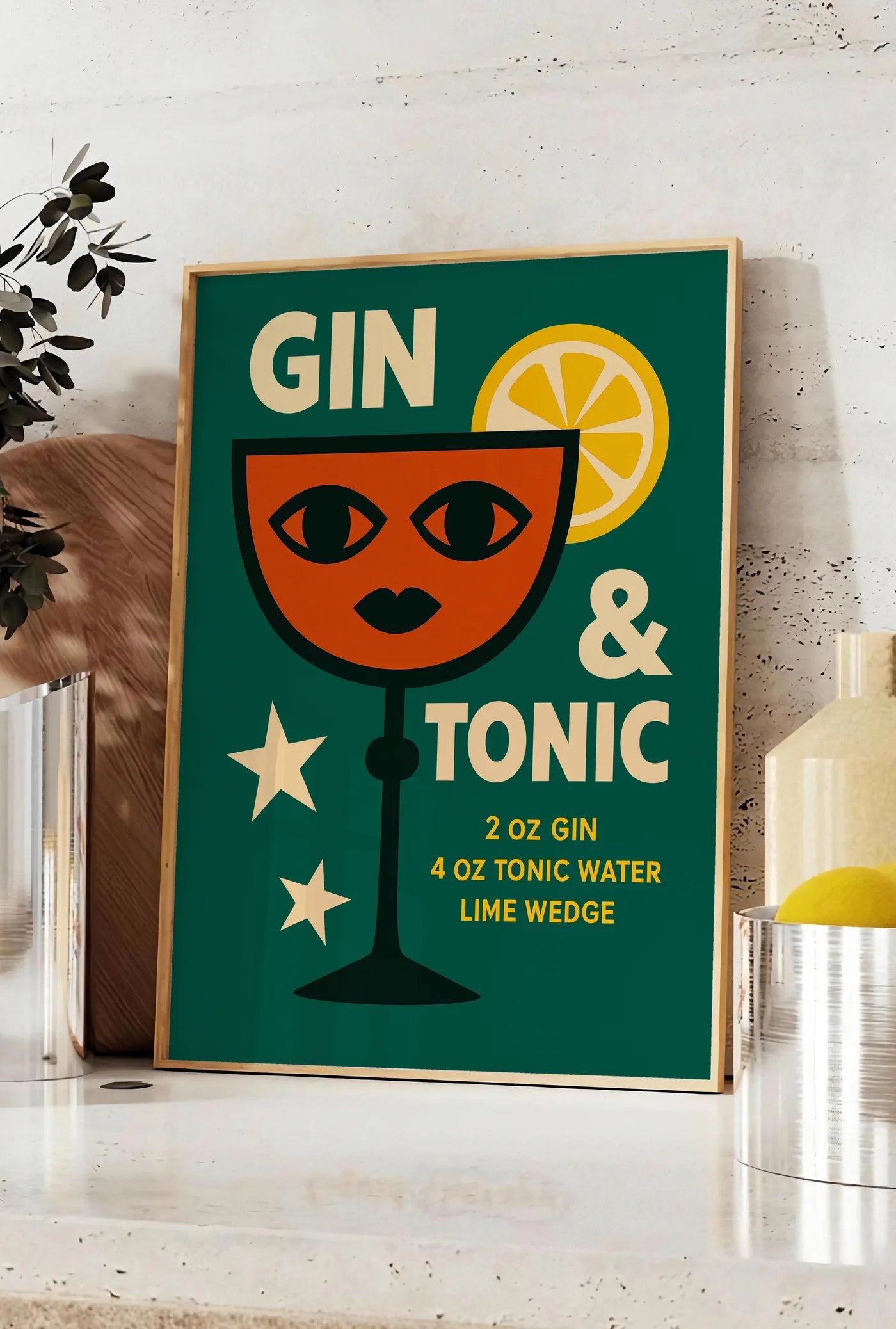 Affiche affiche gin tonic pop-art, posee sur un plan de travail de cuisine en pierre claire, entre une branche d'eucalyptus en vase et un bocal de citrons