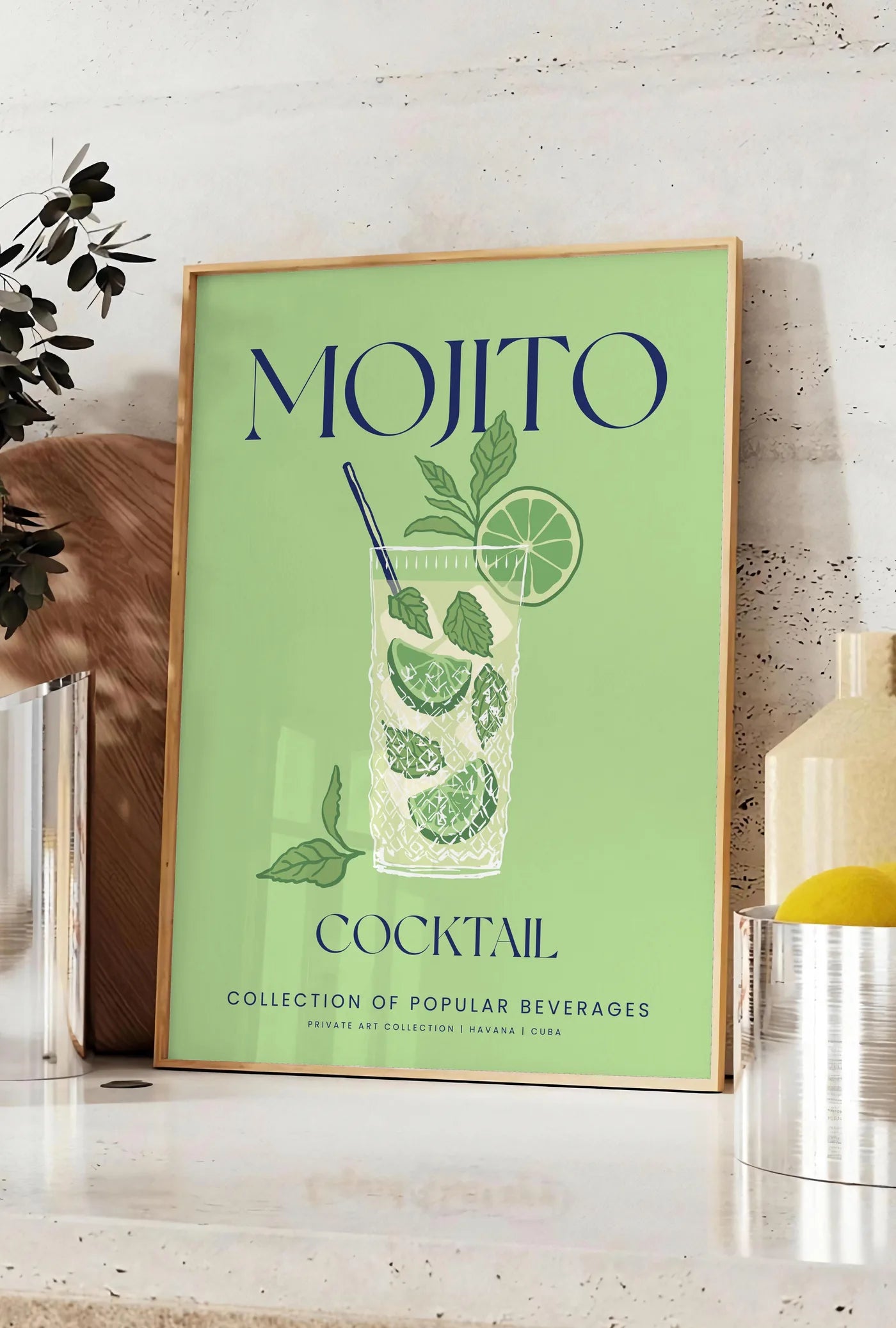 Affiche affiche mojito minimaliste, posee sur un plan de travail de cuisine en pierre claire, entre une branche d'eucalyptus en vase et un bocal de citrons