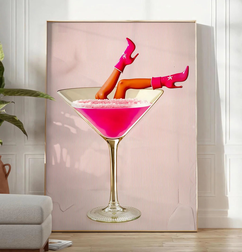 Reproduction affiche cocktail rose kitsch, posee au sol dans un salon minimaliste clair, a cote d'un canape beige et d'une plante verte, sur un parquet clair