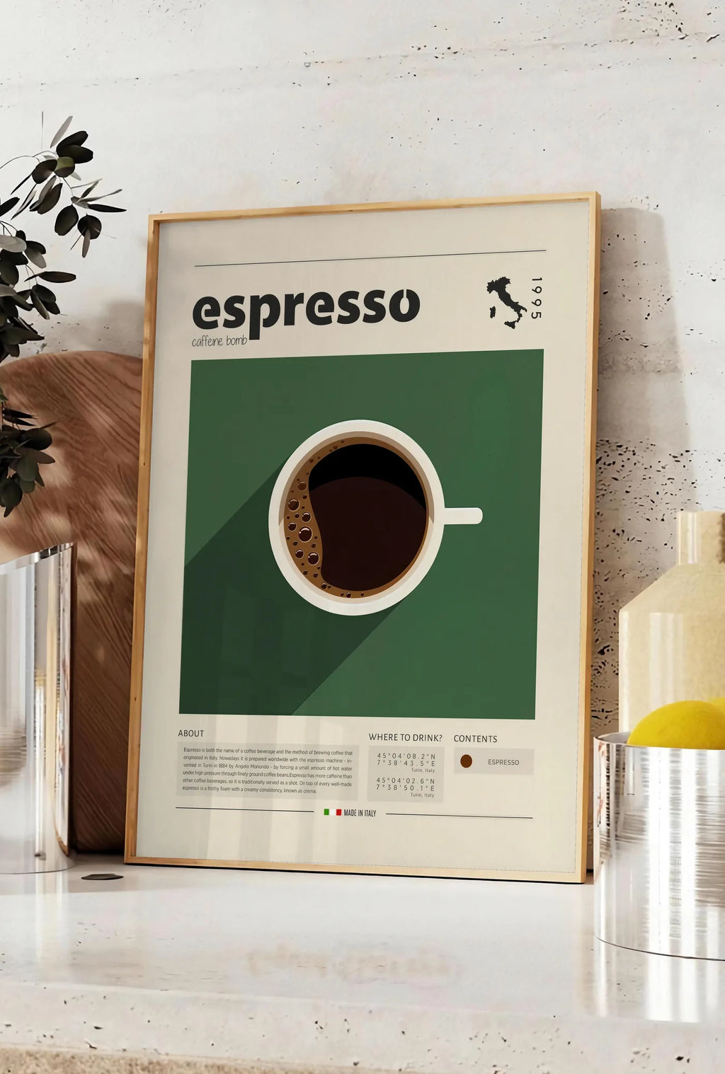 Affiche tasse d'espresso vue de dessus sur fond vert, posee sur un plan de travail de cuisine en pierre claire, entre une branche d'eucalyptus en vase et un bocal de citrons