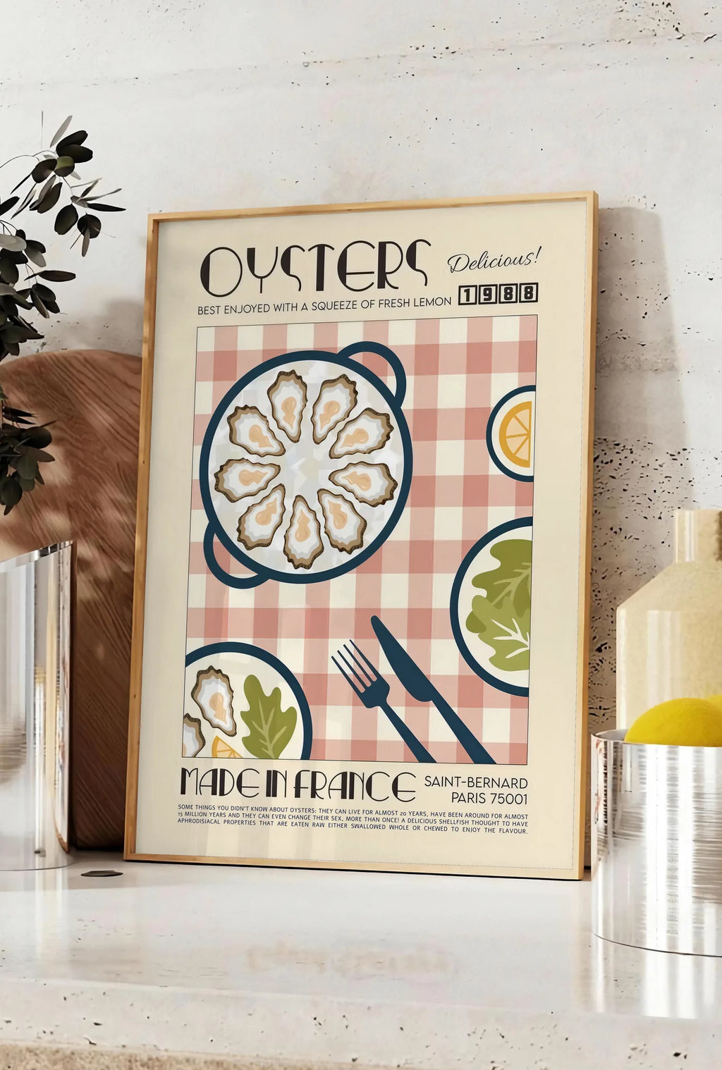 Affiche affiche huitres retro, posee sur un plan de travail de cuisine en pierre claire, entre une branche d'eucalyptus en vase et un bocal de citrons
