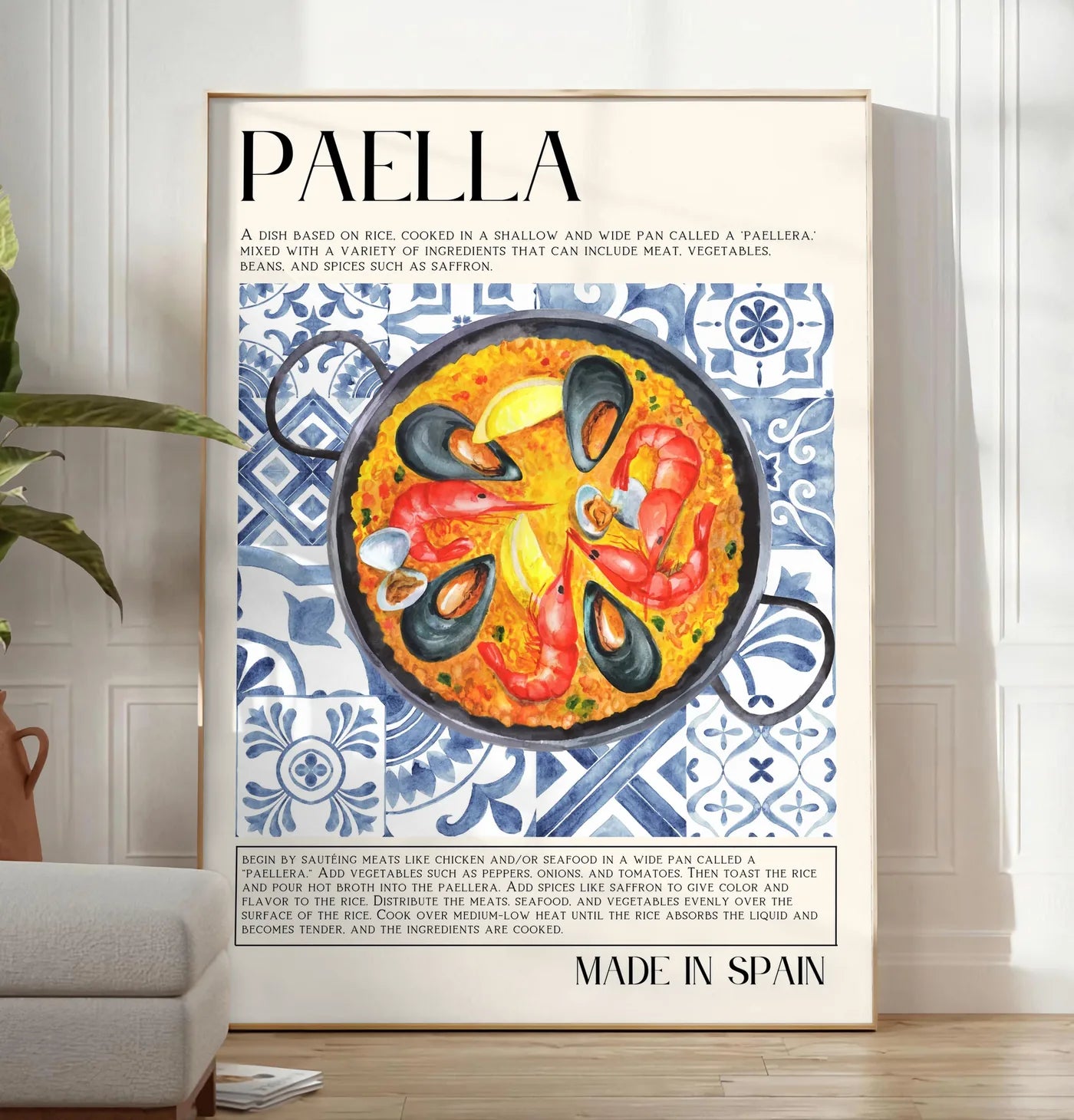 Reproduction affiche paella aquarelle, posee au sol dans un salon minimaliste clair, a cote d'un canape beige et d'une plante verte, sur un parquet clair