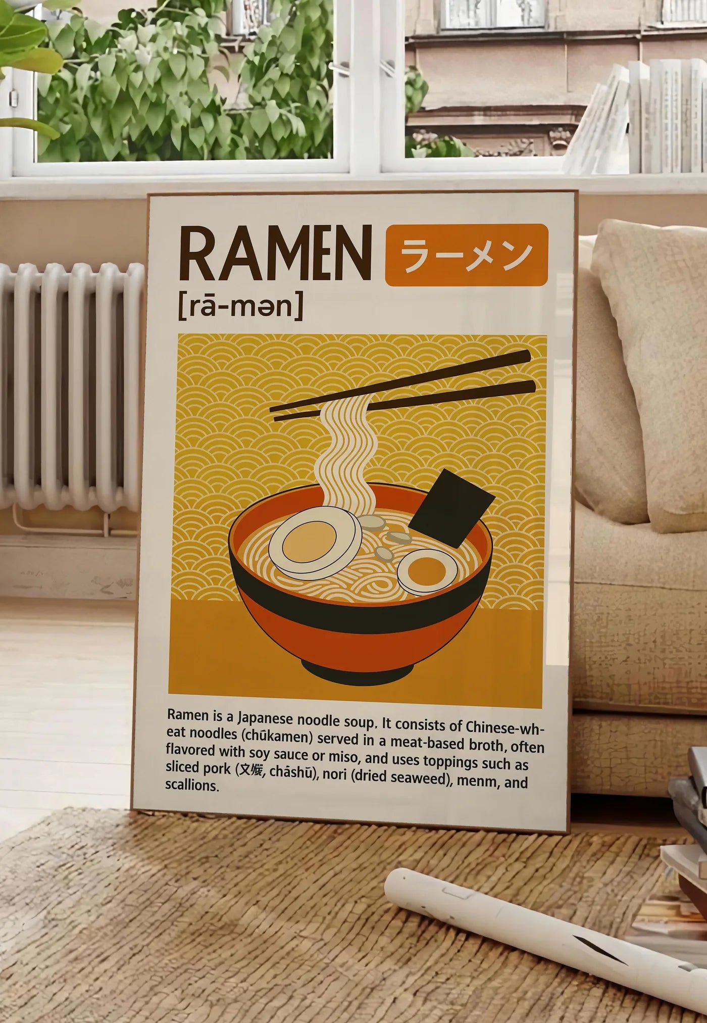 Poster affiche ramen cuisine, posee au sol dans un salon parisien, devant une grande fenetre donnant sur un immeuble haussmannien, entre un ficus et un canape creme