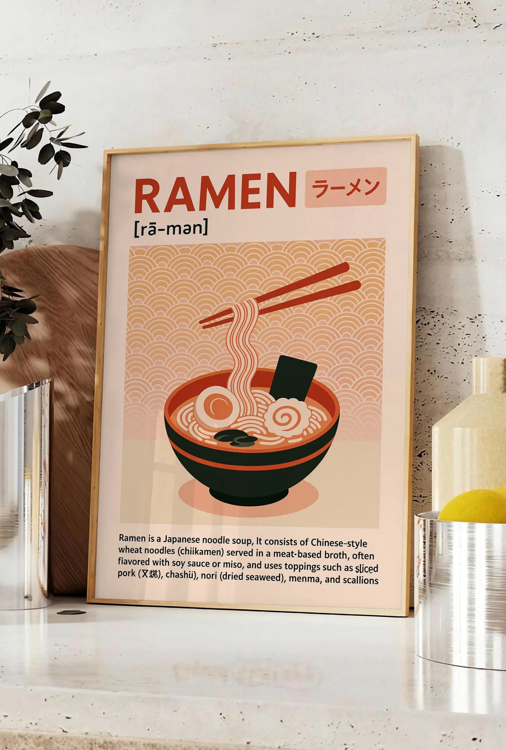 Affiche affiche ramen cuisine, posee sur un plan de travail de cuisine en pierre claire, entre une branche d'eucalyptus en vase et un bocal de citrons