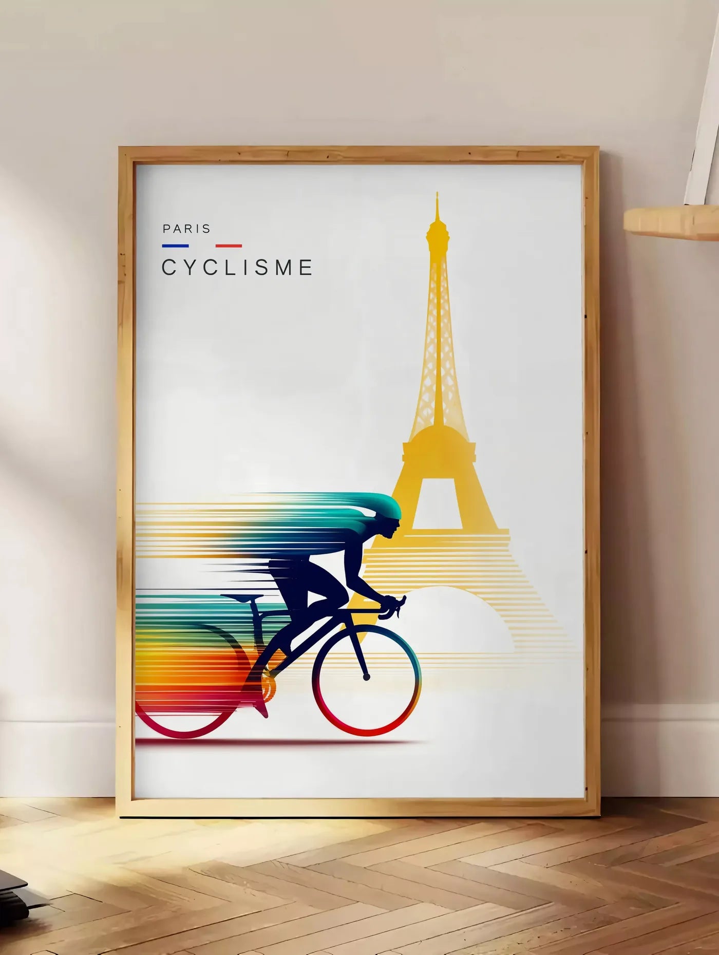 Estampe cycliste stylisé en silhouette filée, posee au sol dans un coin salon, sur un parquet a chevrons, pres d'une table d'appoint en chene chargee de livres