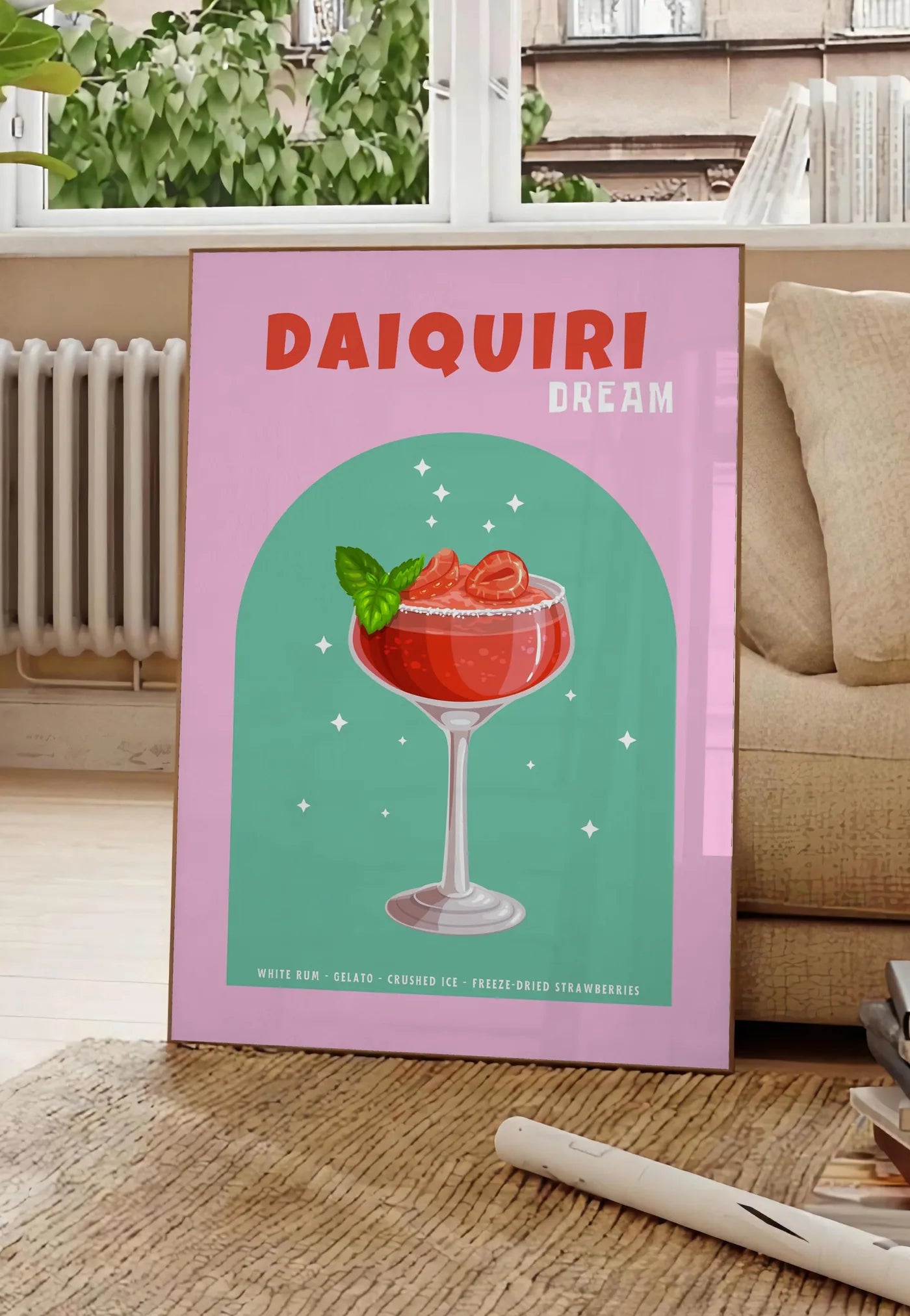 Poster affiche cocktail Daiquiri fraise, posee au sol dans un salon parisien, devant une grande fenetre donnant sur un immeuble haussmannien, entre un ficus et un canape creme