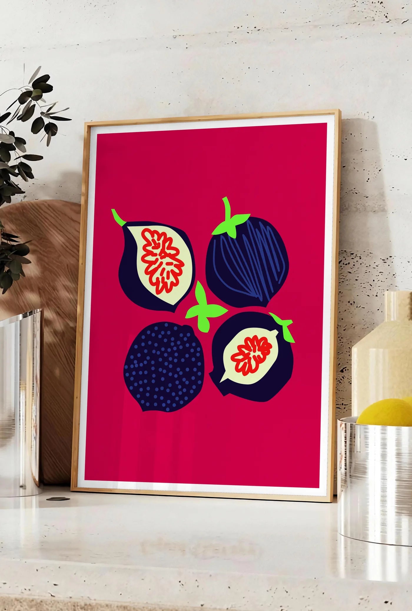 Affiche affiche cuisine figues fruit, posee sur un plan de travail de cuisine en pierre claire, entre une branche d'eucalyptus en vase et un bocal de citrons