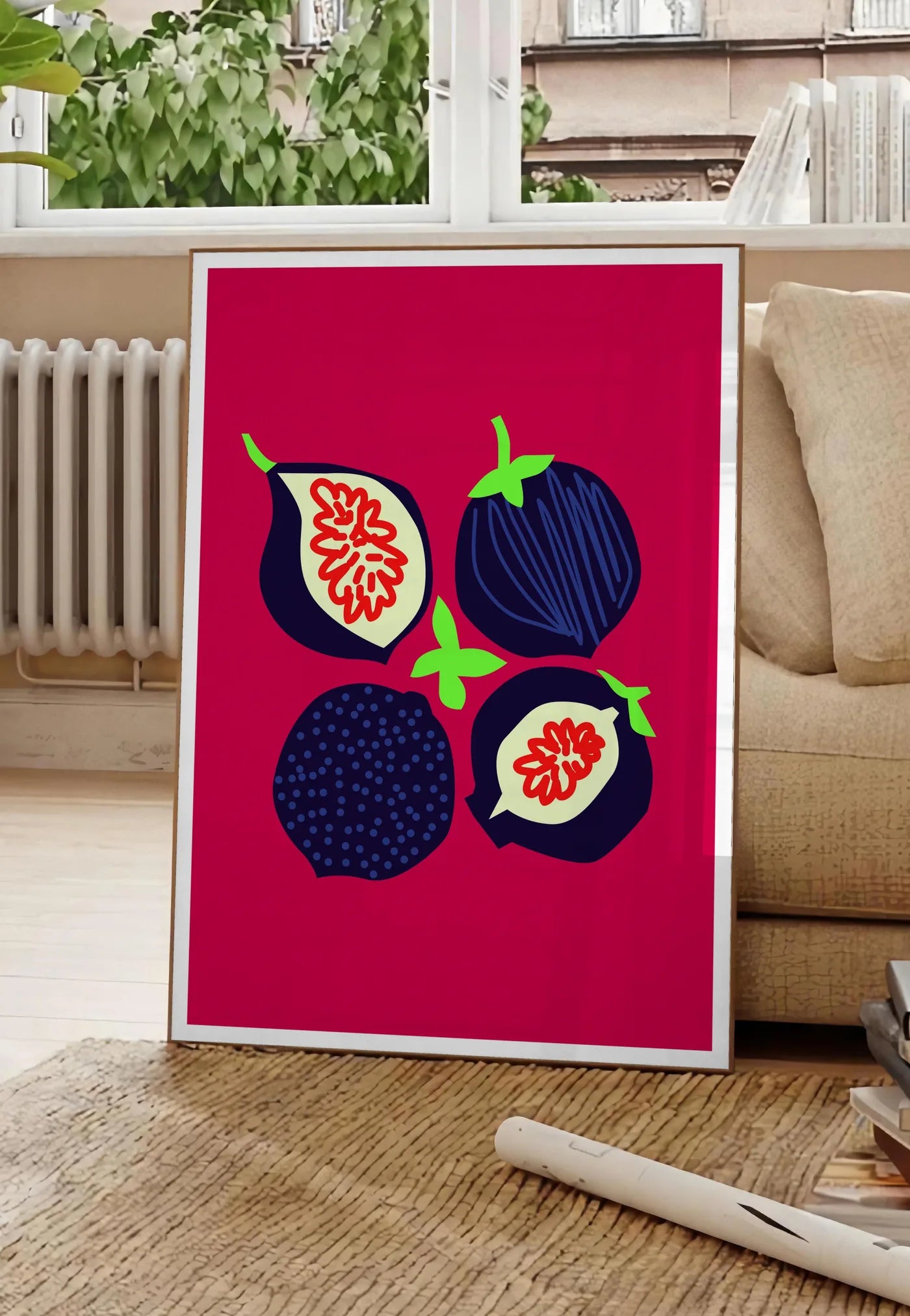 Poster affiche cuisine figues fruit, posee au sol dans un salon parisien, devant une grande fenetre donnant sur un immeuble haussmannien, entre un ficus et un canape creme