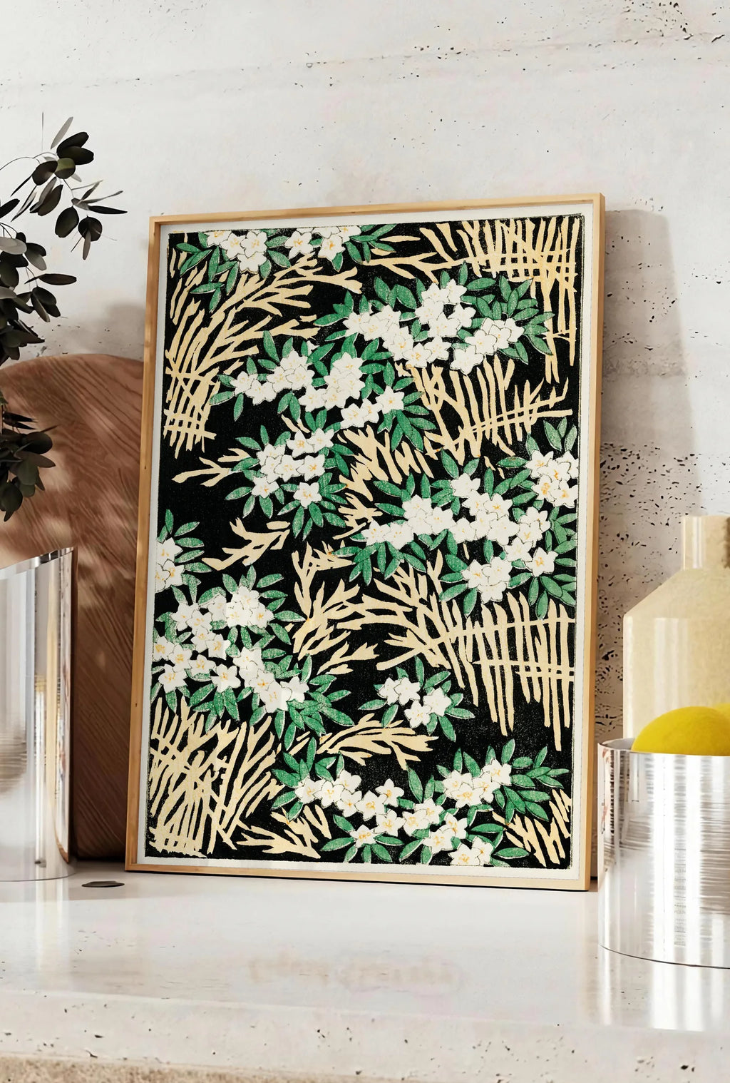 Affiche affiche fleurs blanches sur fond noir art japonais, posee sur un plan de travail de cuisine en pierre claire, entre une branche d'eucalyptus en vase et un bocal de citrons