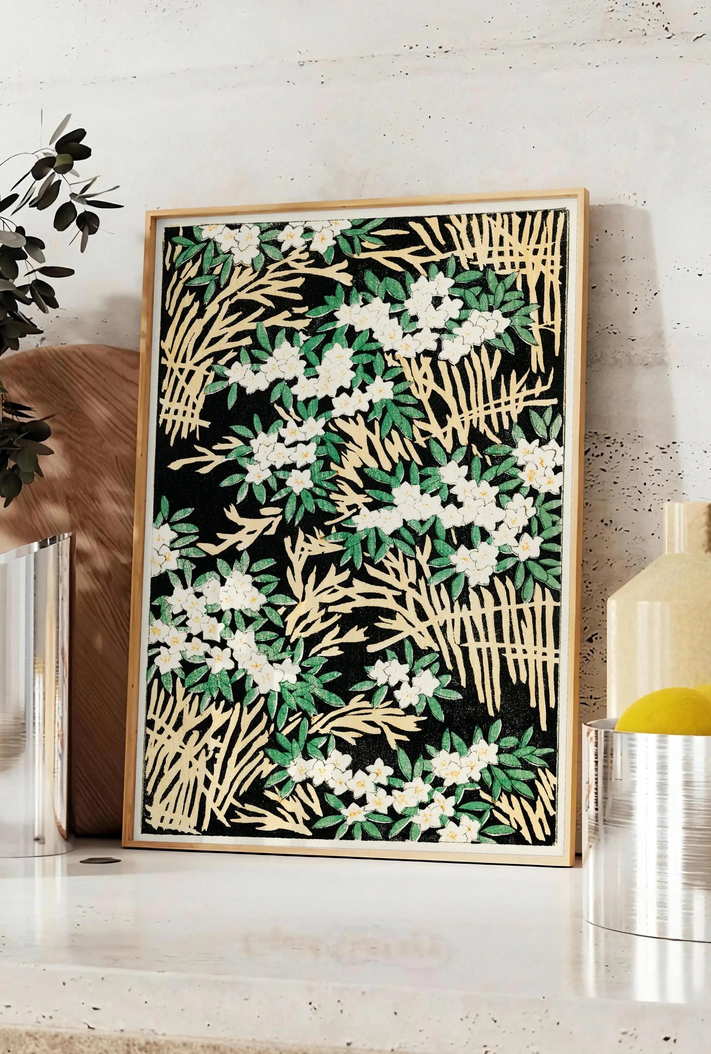 Affiche affiche fleurs blanches sur fond noir art japonais, posee sur un plan de travail de cuisine en pierre claire, entre une branche d'eucalyptus en vase et un bocal de citrons