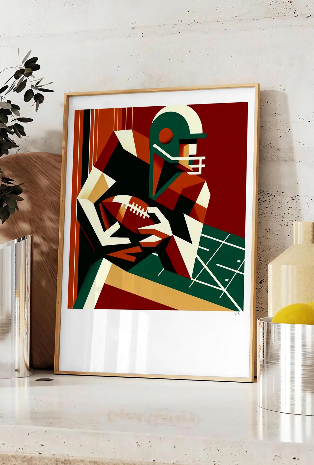 Affiche joueur de football américain stylisé tenant un ballon ovale, posee sur un plan de travail de cuisine en pierre claire, entre une branche d'eucalyptus en vase et un bocal de citrons