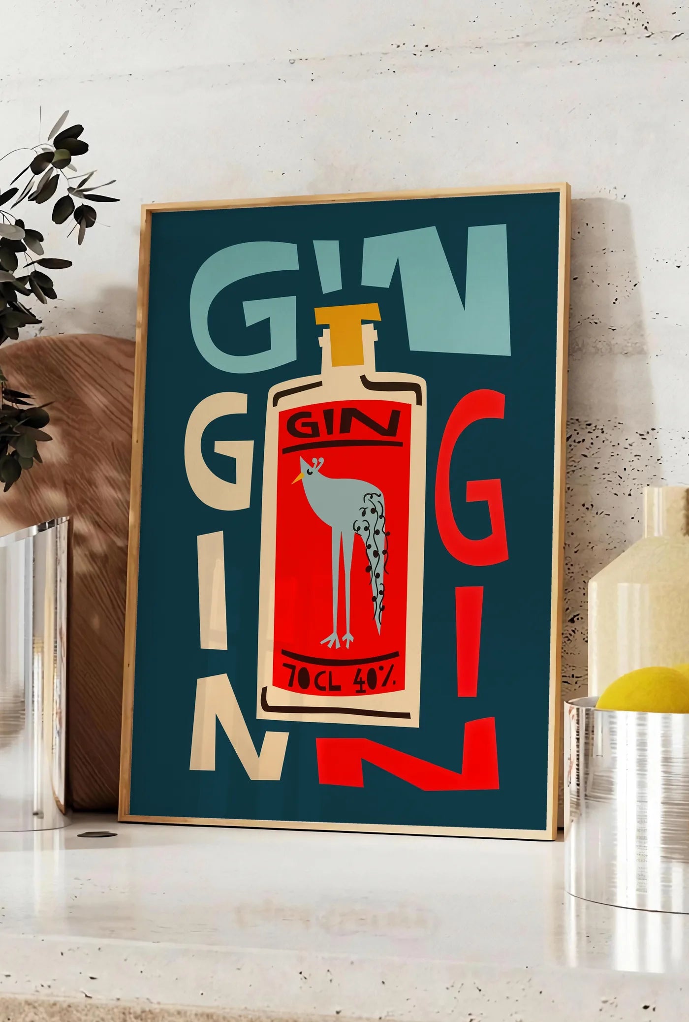Affiche affiche cocktail gin, posee sur un plan de travail de cuisine en pierre claire, entre une branche d'eucalyptus en vase et un bocal de citrons