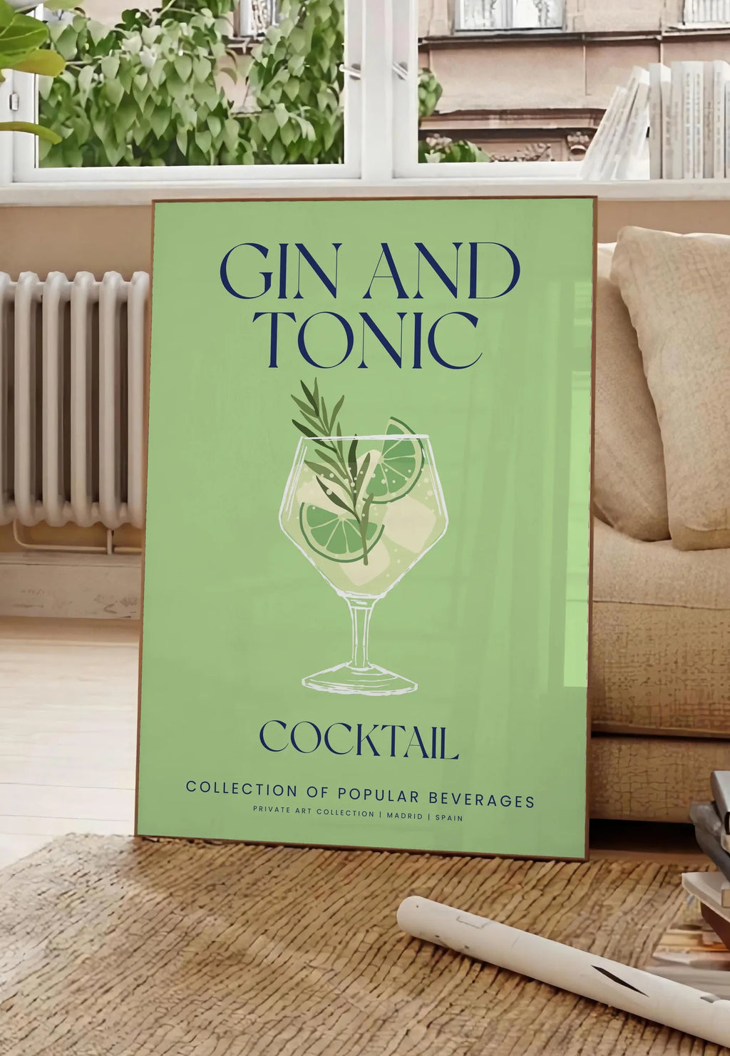 Poster affiche cocktail Gin Tonic, posee au sol dans un salon parisien, devant une grande fenetre donnant sur un immeuble haussmannien, entre un ficus et un canape creme